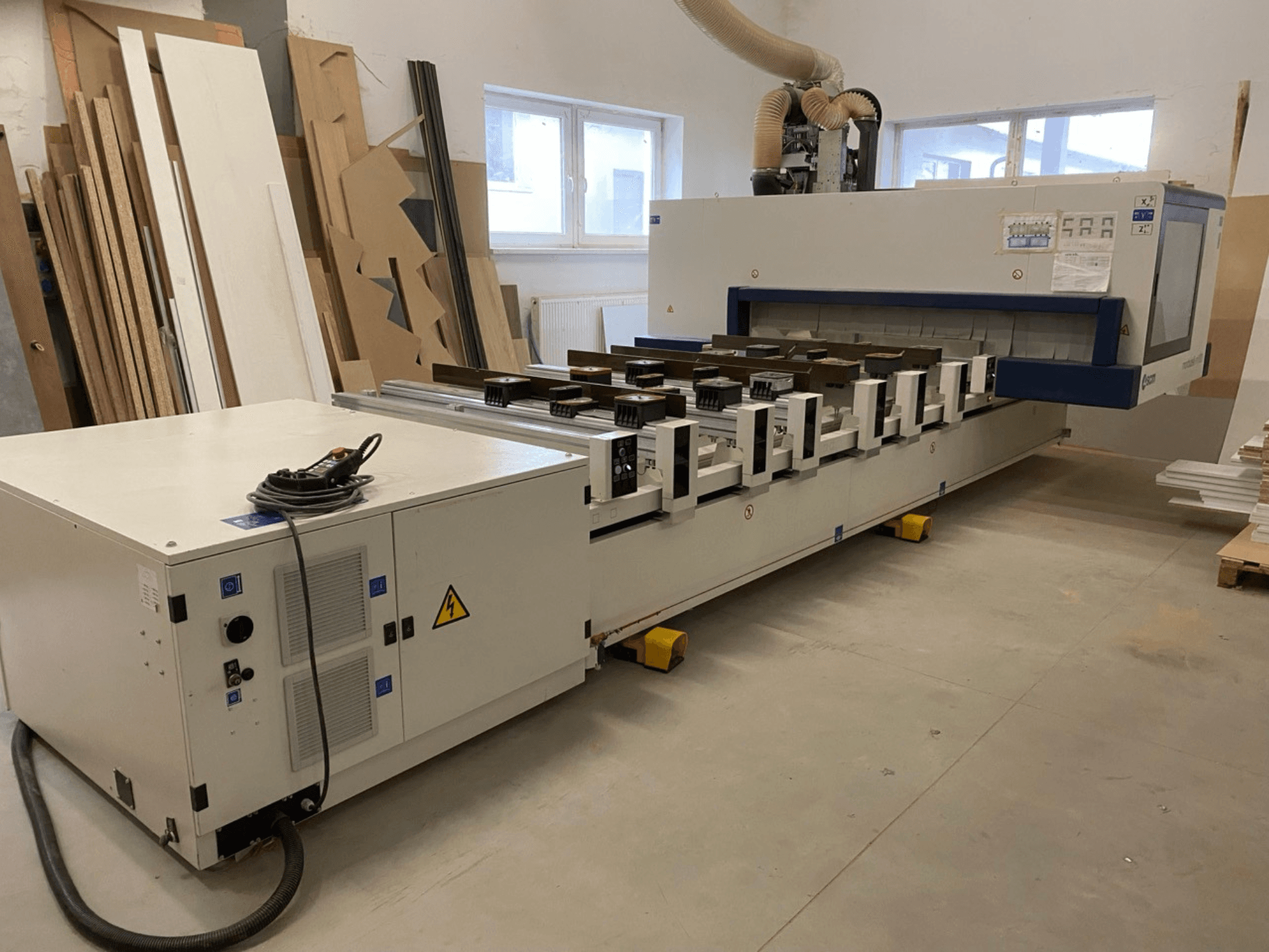 SCM Morbidelli ražotais M100 CNC koka apstrādes centrs darbnīcā — attēlā redzams priekšskats ar vadības paneli un putekļu nosūces sistēmu.