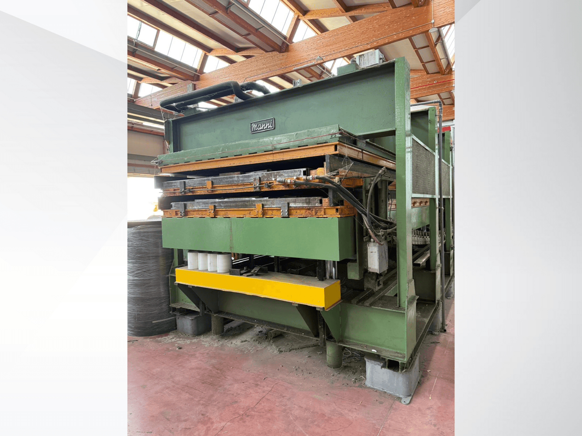 Manni hidrauliskā prese, skats no sāniem, ar zaļu metāla korpusu, dzeltenu pamatni un vairākām redzamām hidrauliskajām līnijām.