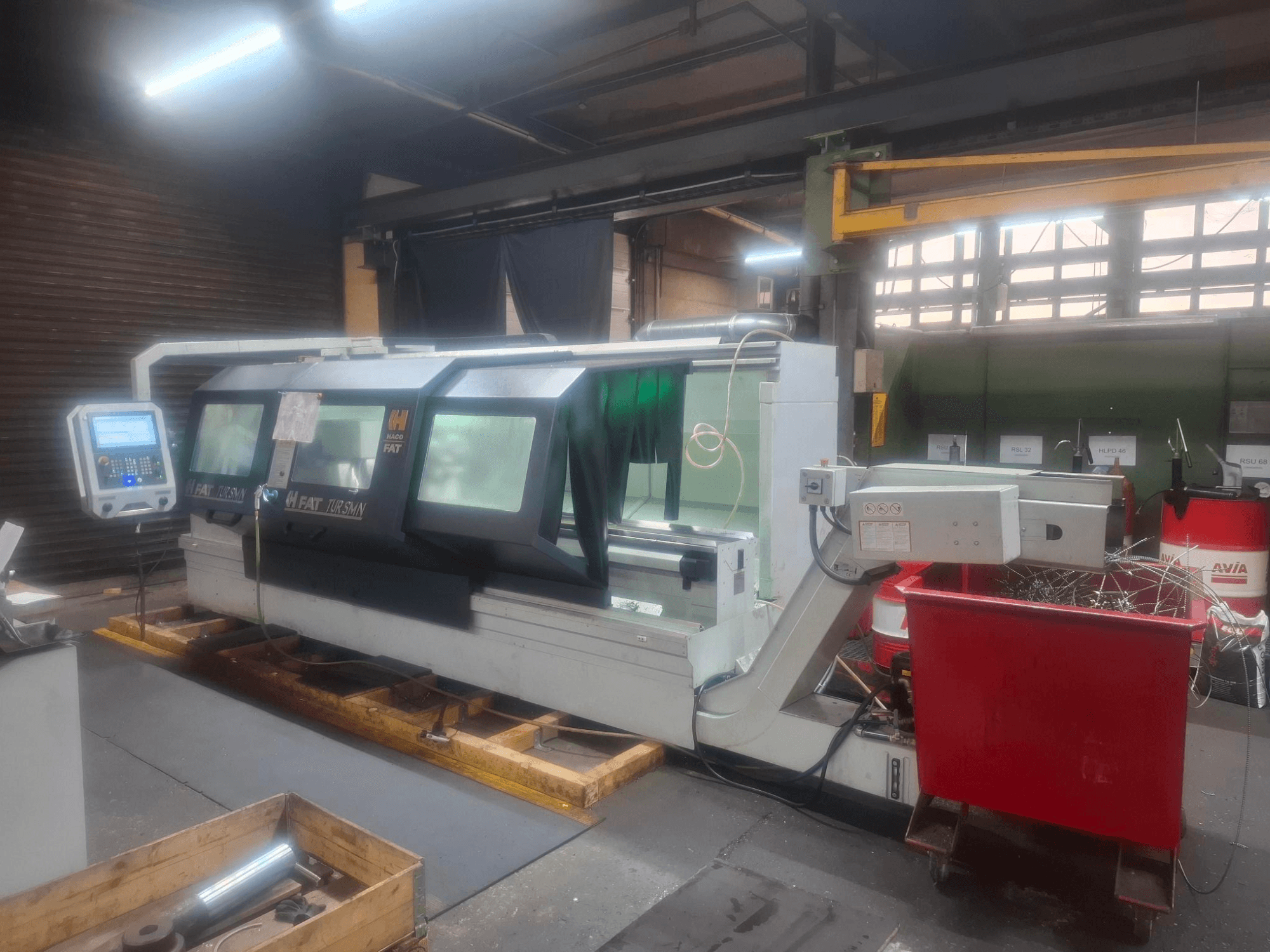 FAT Tursan CNC darbagaldi ar vadības paneli, kas novietoti uz koka paliktņiem darbnīcā.