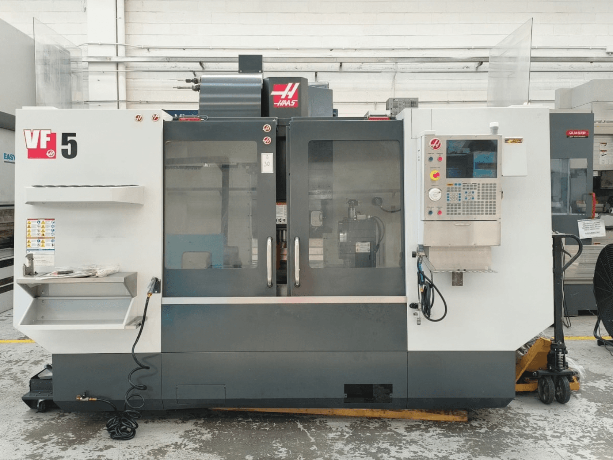 HAAS VF 5/40 vertikālā apstrādes centra skats no priekšpuses, kurā redzams vadības panelis un stikla durvis.