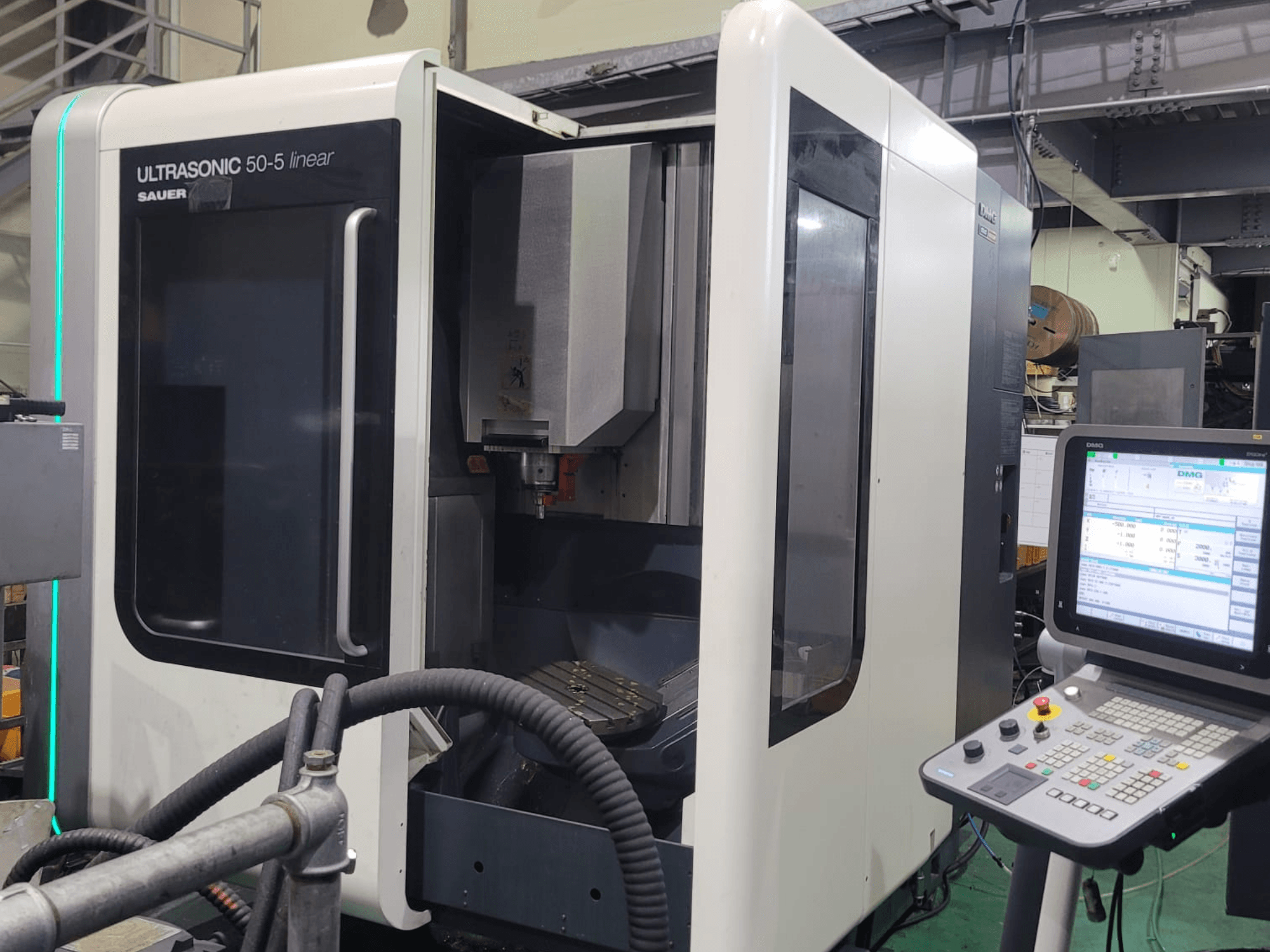 DMG ULTRASONIC 50-5 lineārais universālais apstrādes centrs, priekšējais skats ar vadības paneli un redzamo darba zonu.