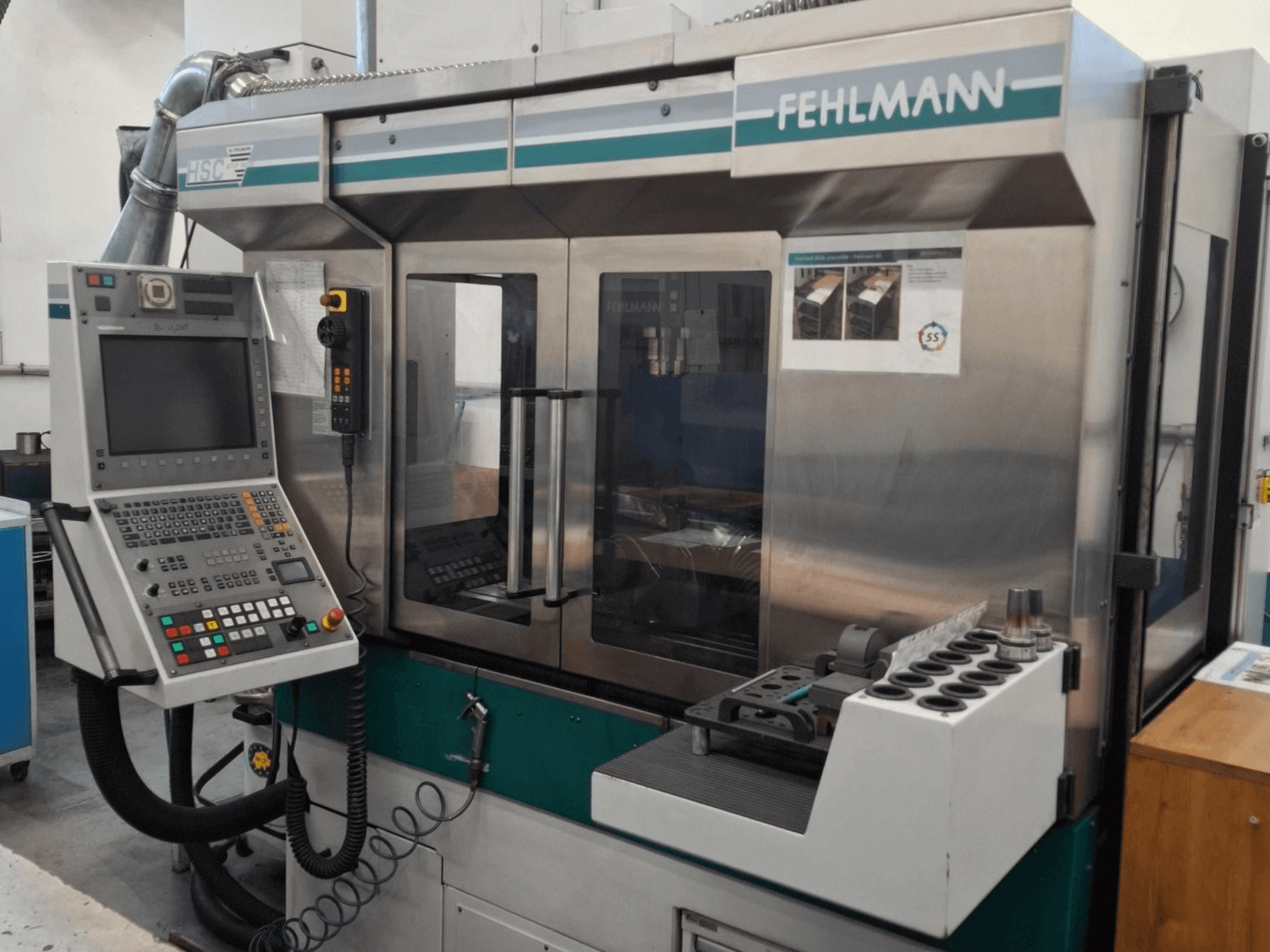 Fehlmann HSC 20 CNC darbgalds, skats no priekšpuses, ar vadības paneli, metāla korpusu un instrumentu turētāju ar vairākām spraugām.