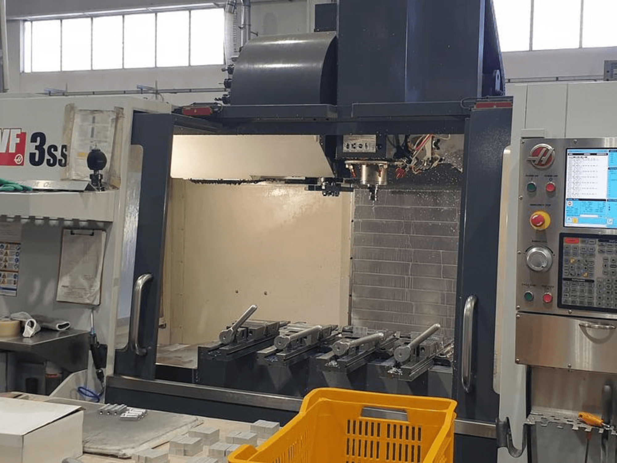 HAAS VF-3SS vertikālais apstrādes centrs, priekšējais skats ar CNC vadības paneli, instrumentiem un oranžo grozu.