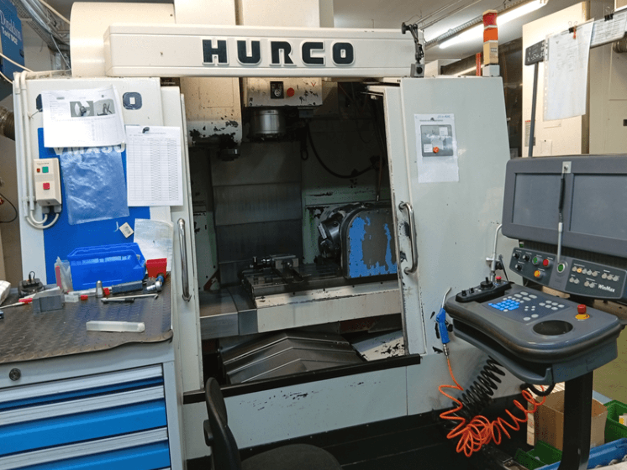 Hurco VMX 30T vertikālais apstrādes centrs, skats no priekšpuses, kurā redzams vadības panelis, darba vieta un daļēji atvērtas durvis.