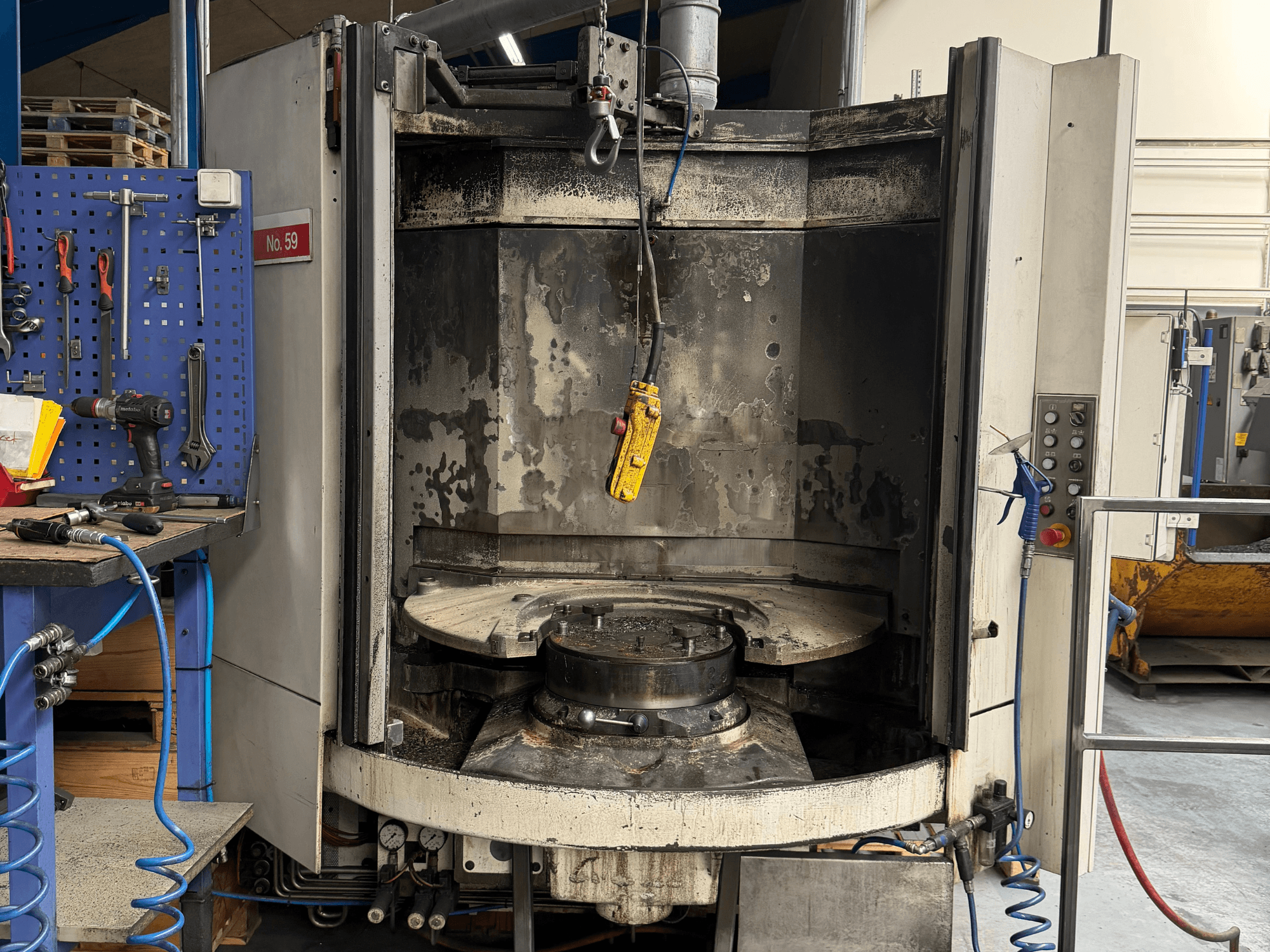 Horizontālais apstrādes centrs HELLER MC 16 no priekšpuses, kurā redzams tukšs darba galds un vadības panelis, darbnīcā.