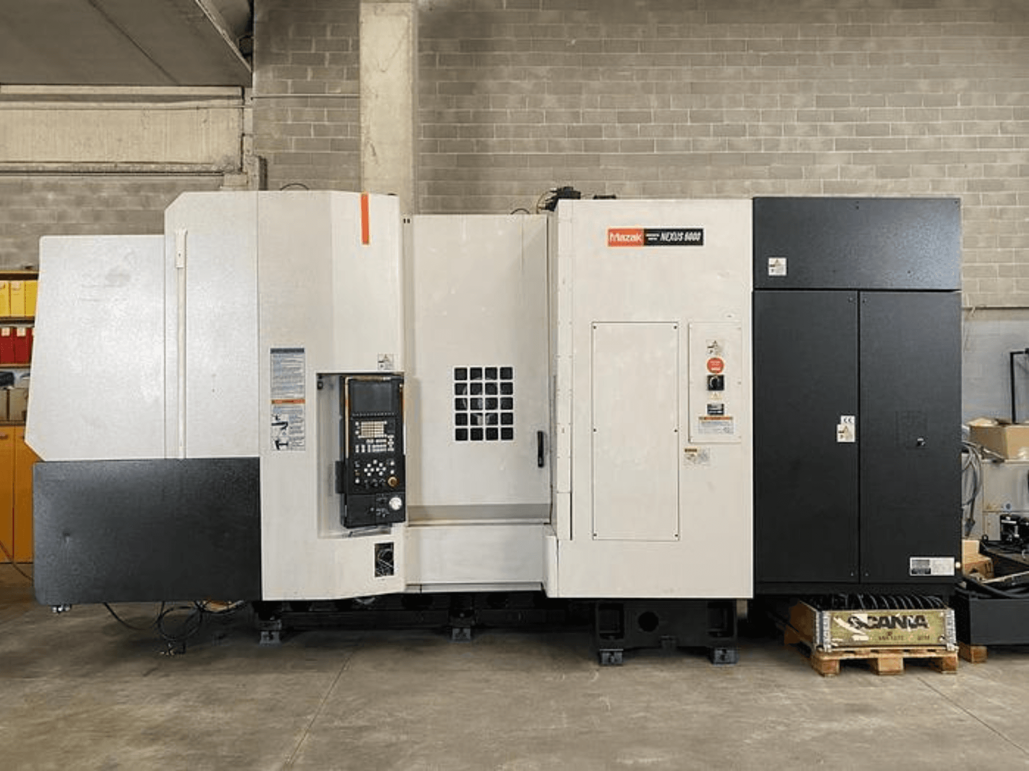 Mazak NEXUS 6400 CNC virpa, skats no priekšpuses, ar vadības paneli, barošanas slēdzi un divkrāsu balto un melno korpusu.