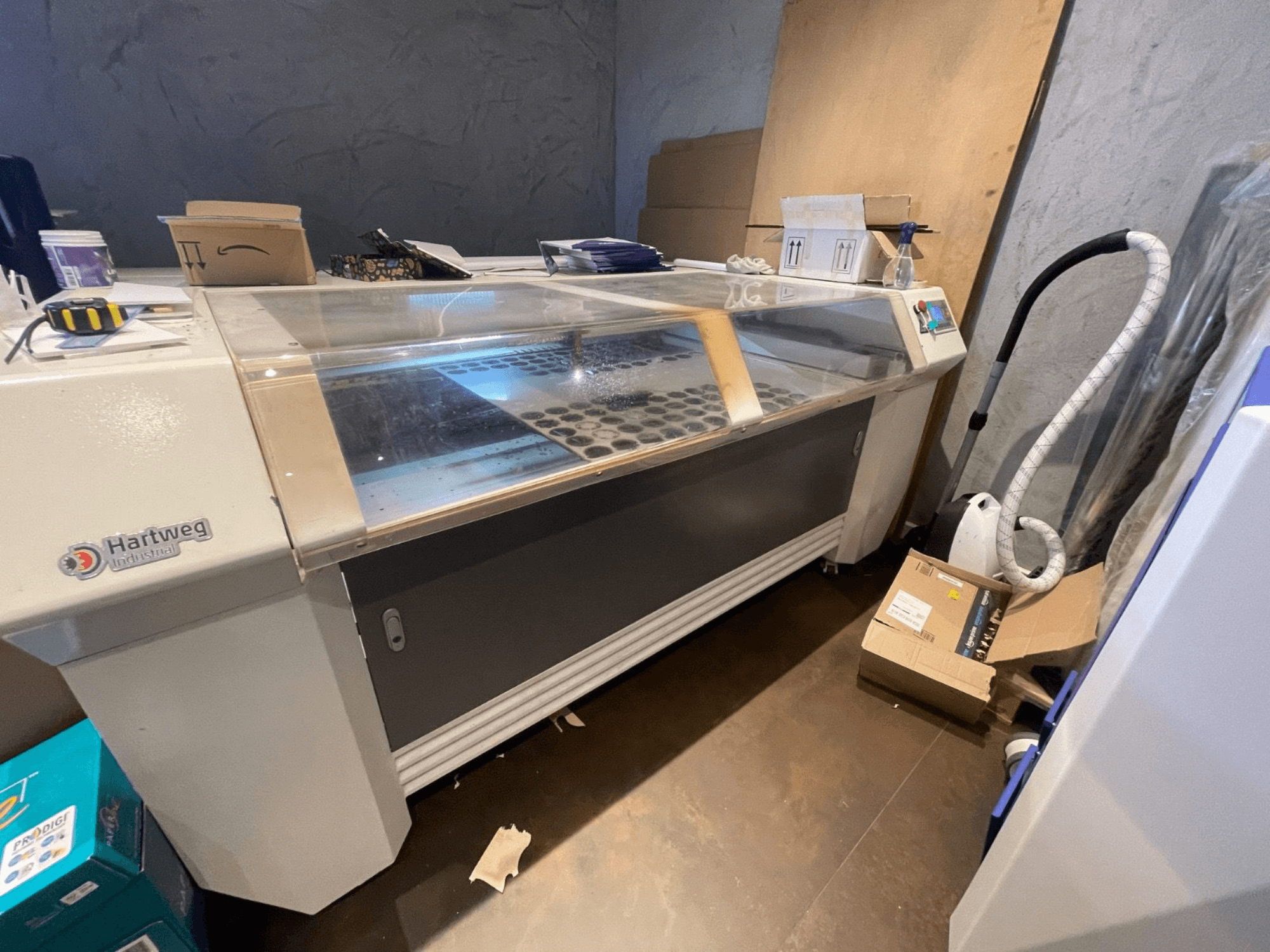 CO2 lāzera griešanas iekārta Bodor CL-1610XUF sānu skatā, parādot darba zonu ar materiālu slotiem un vadības paneli.