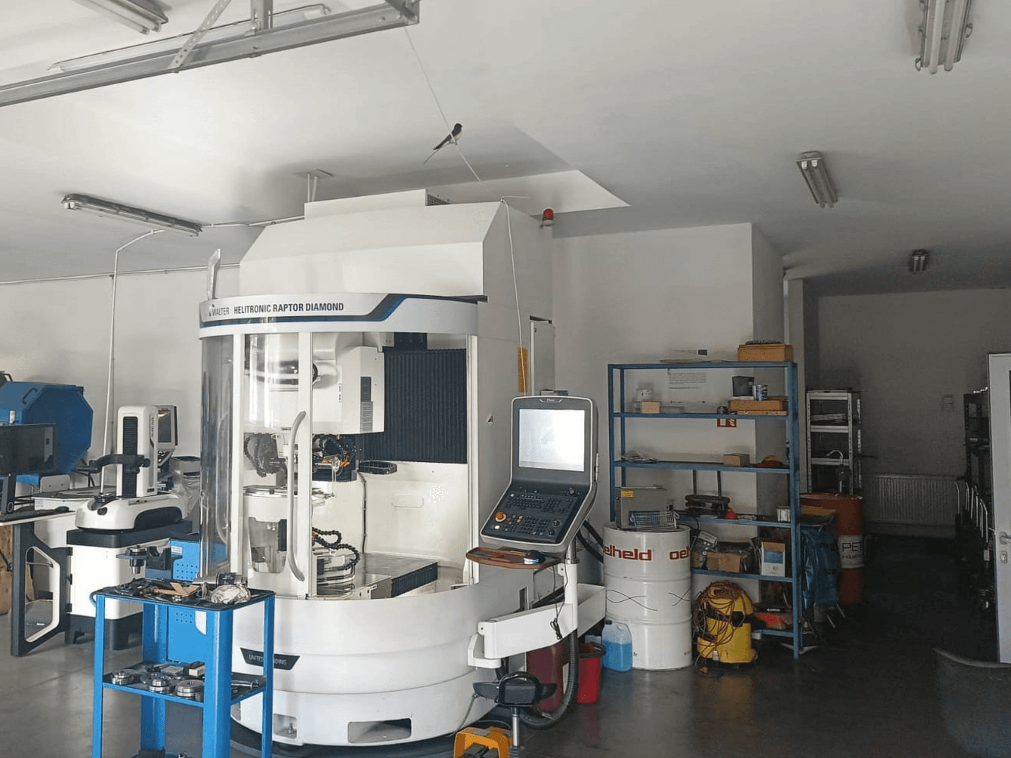 WALTER HELITRONIC RAPTOR DIAMOND cilindriskās slīpēšanas mašīna darbnīcā, skats no sāniem ar vadības pulti un instrumentiem blakus.