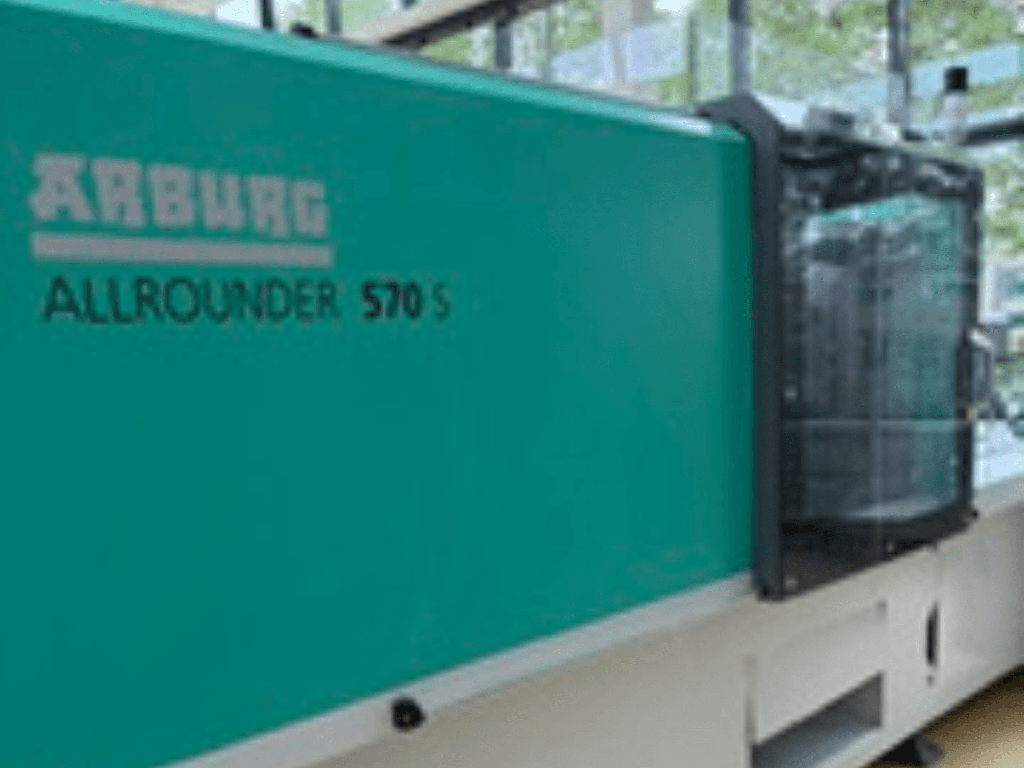 Arburg ALLROUNDER 570 S 1600-290 priekšējais skats, ar tējas krāsas ārpusi un iesmidzināšanas bloku, kas parāda daļu no mašīnas konstrukcijas.