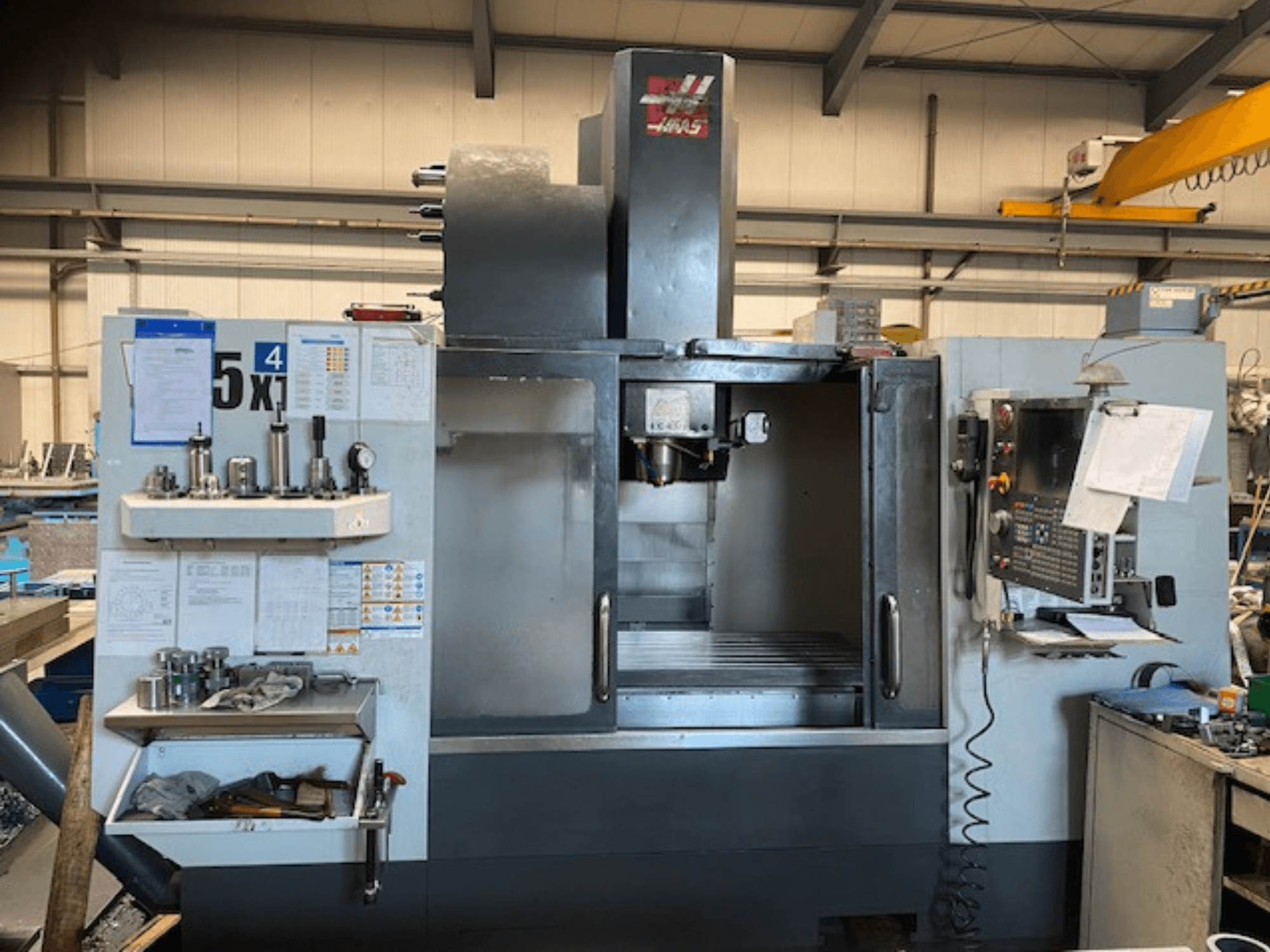 Haas VF-5 vertikālais apstrādes centrs, skats no priekšpuses, kurā redzams vadības panelis, instrumentu glabāšanas vieta un vārpstas zona.