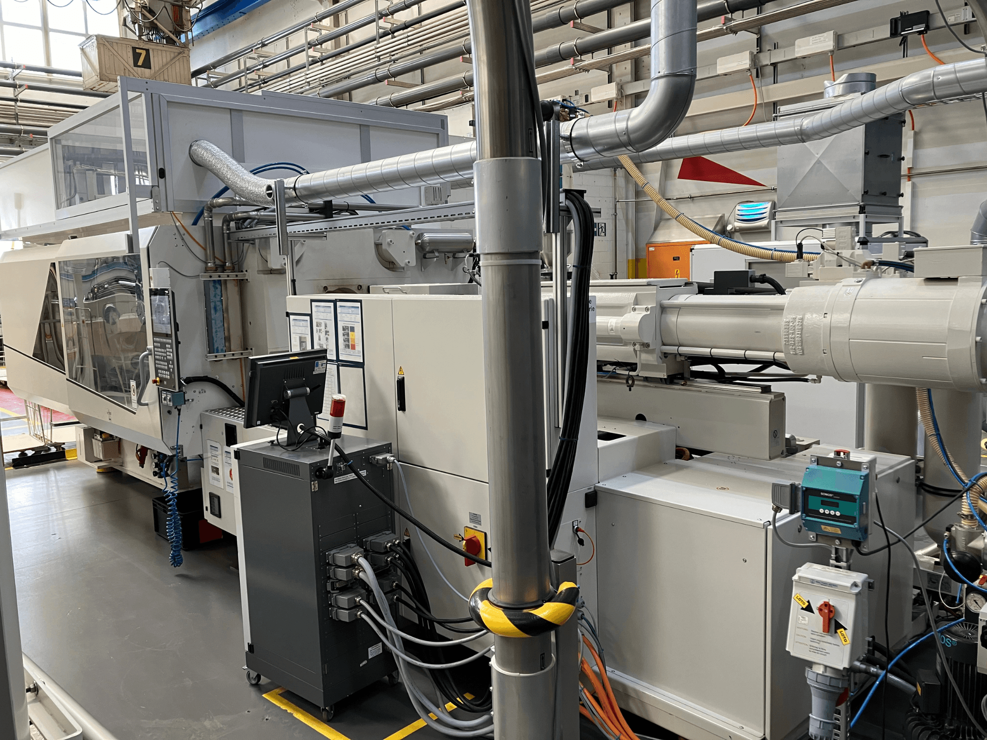 Rūpnieciskās iekārtas ar vadības paneli, skats no priekšpuses, ar cauruļvadiem, elektrības komponentiem un drošības elementiem.