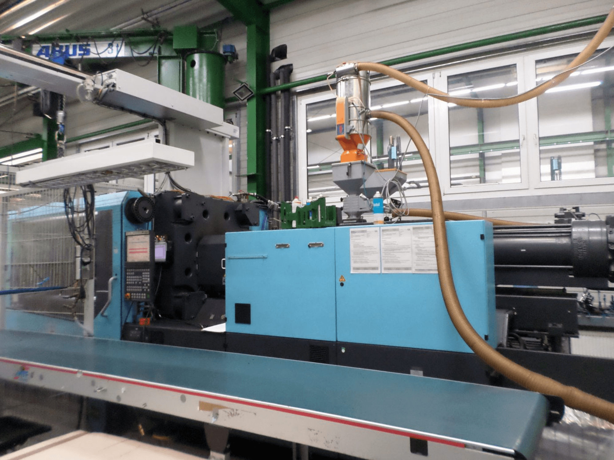 DEMAG D 420 hidrauliskās injekcijas formēšanas mašīnas skats no priekšpuses, kurā redzams vadības panelis, piltuve un hidrauliskās detaļas.