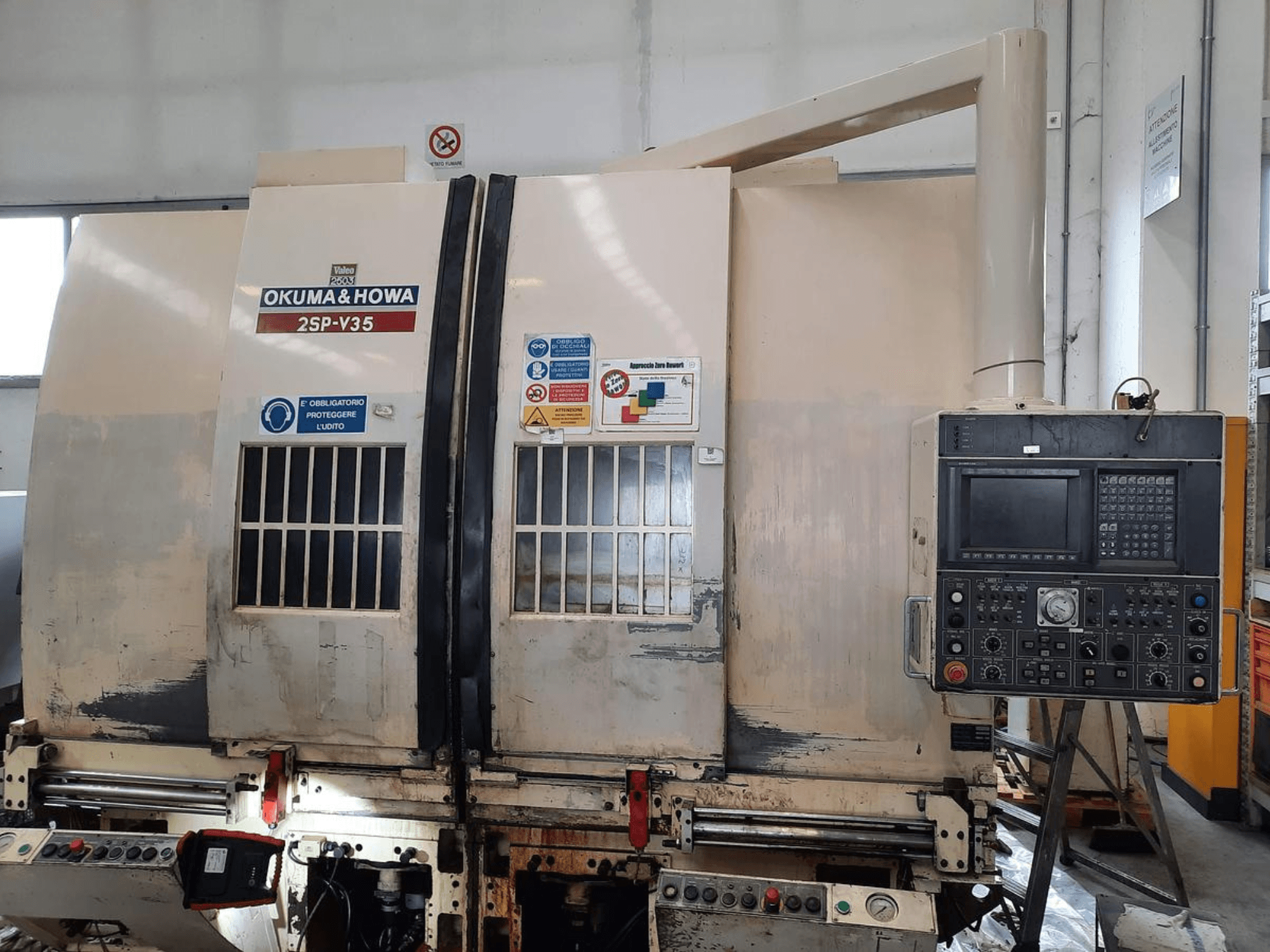 OKUMA & HOWA 2SP-V35 CNC mašīna no priekšpuses, ar vadības paneli ar dažādām pogām un drošības marķējumiem.