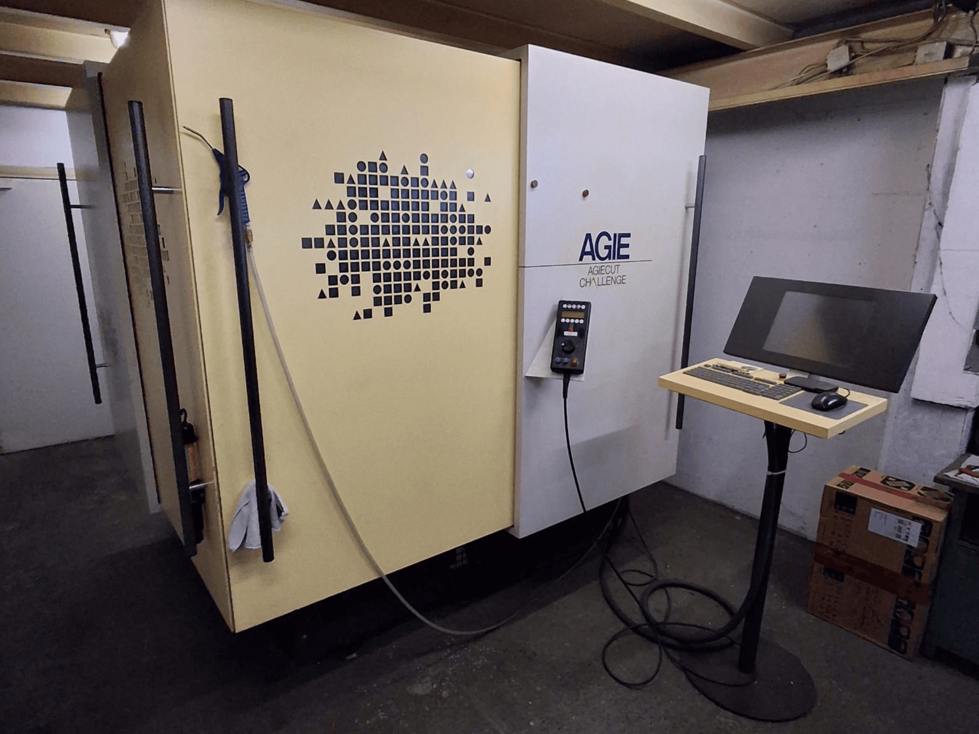 AGIE Agiecut Challenge divvadu elektroerozijas mašīna darbnīcā, ar vadības pulti un monitoru uz statņa, skats no priekšpuses.