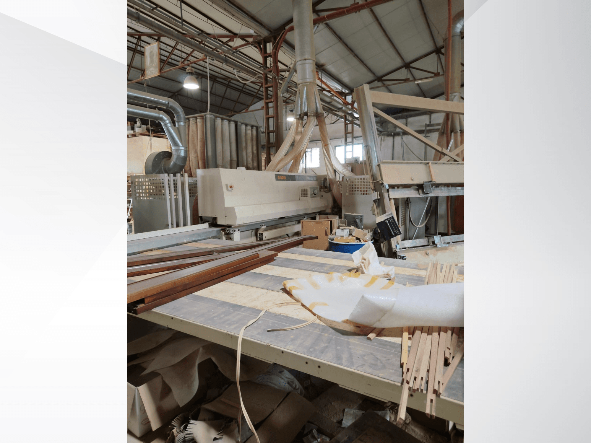 CNC kokapstrādes centrs SCM Windor60 darbnīcā, skatīts no sāniem, ar koka paneļiem un putekļu nosūces iekārtām.