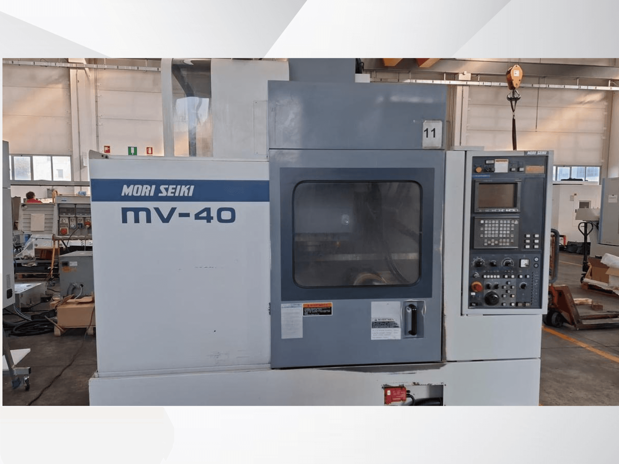 MORI SEIKI MV-40 vertikālās apstrādes centrs, priekšējais skats, kurā redzams vadības panelis un logs, darbnīcā.