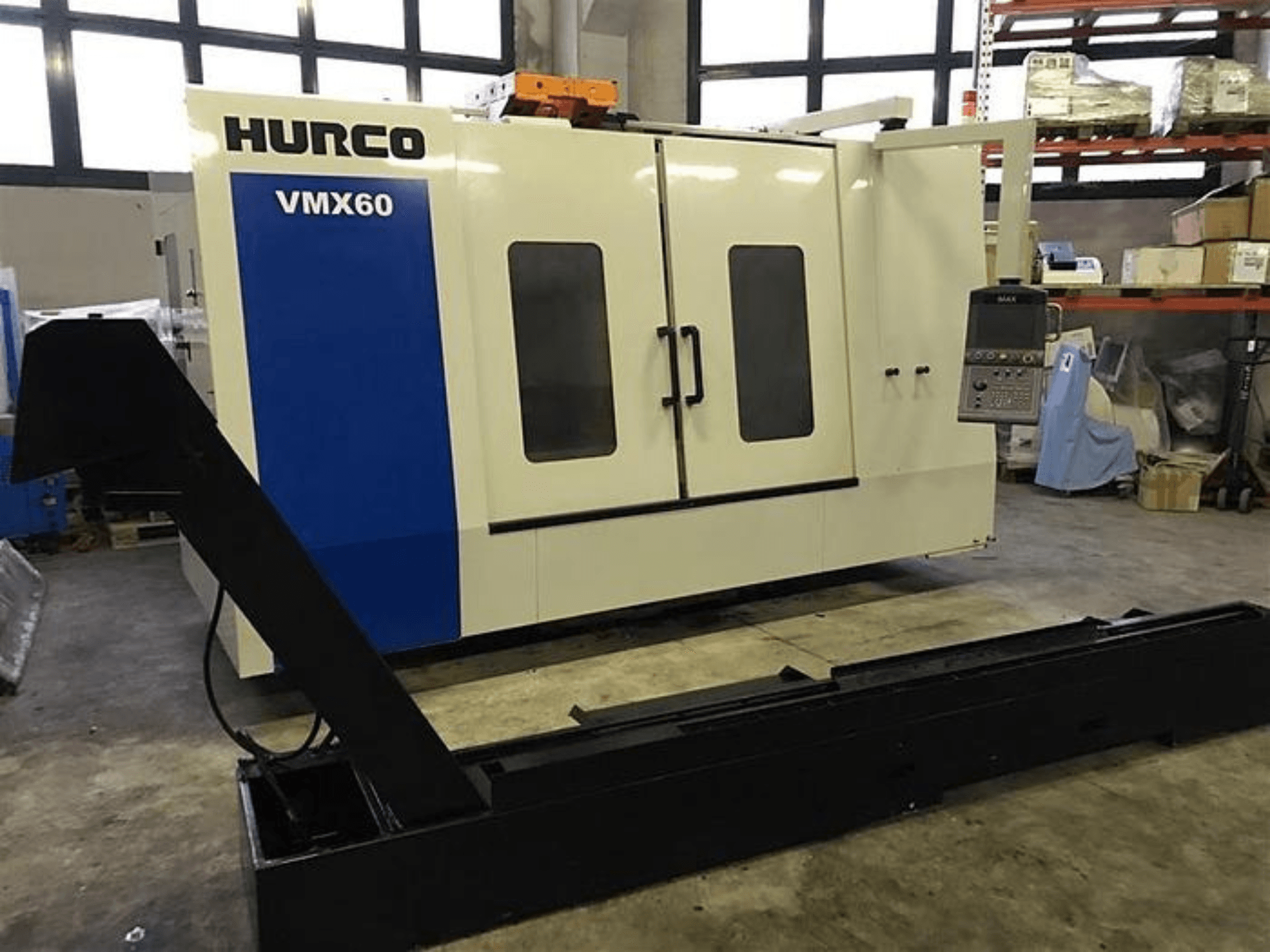 HURCO VMX60 CNC darbnīcā, skats no priekšpuses, ar vadības paneli un pievienotu melnu atbalsta sliedi.