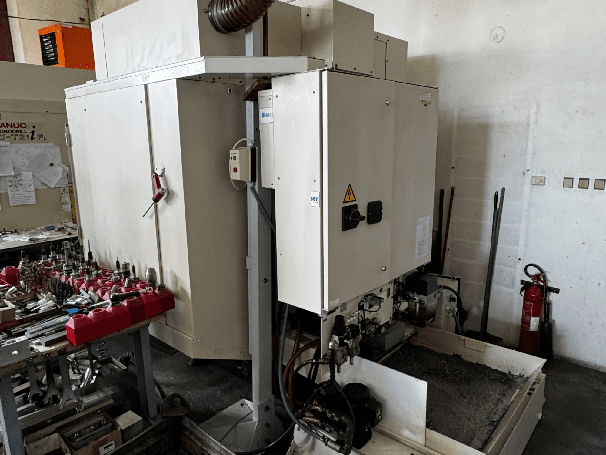 FANUC Robodrill alpha-T21iFL vertikālais apstrādes centrs, sānu skats, kurā redzams vadības panelis, instrumenti un darba vieta.