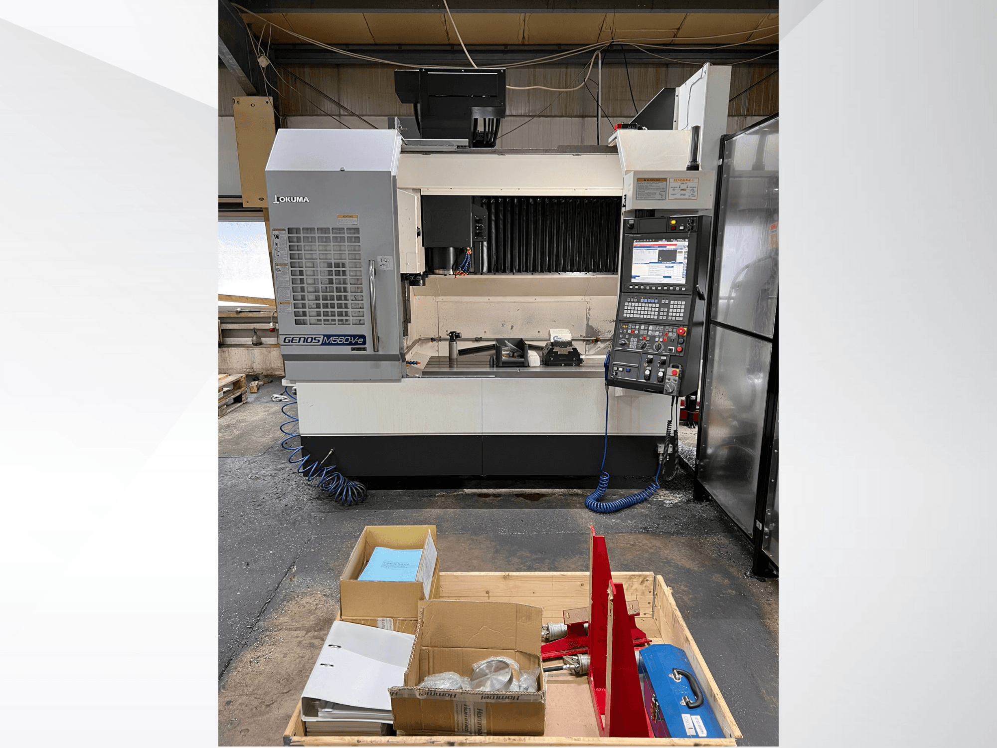 Okuma GENOS M460V-5 vertikālais apstrādes centrs, skats no priekšpuses, redzams vadības panelis un instrumenti uz darba galda.