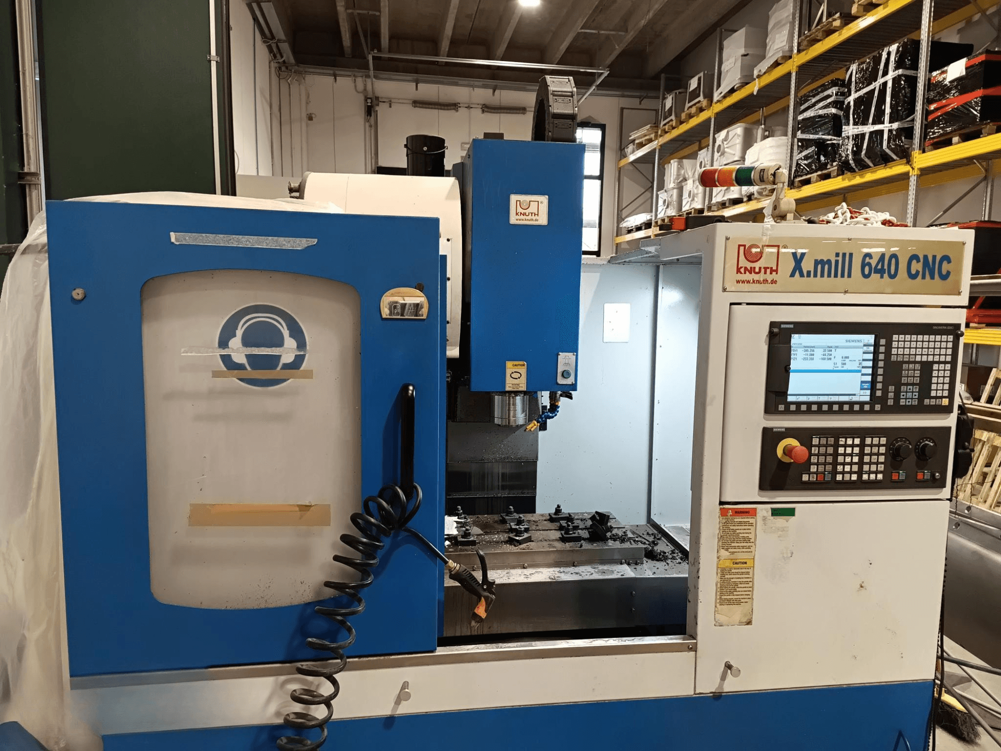 Knuth X.mill 640 CNC darbgalds sānu skatā ar vadības paneli, vārpstas zonu un redzamu apstrādājamo detaļu iestatījumu.