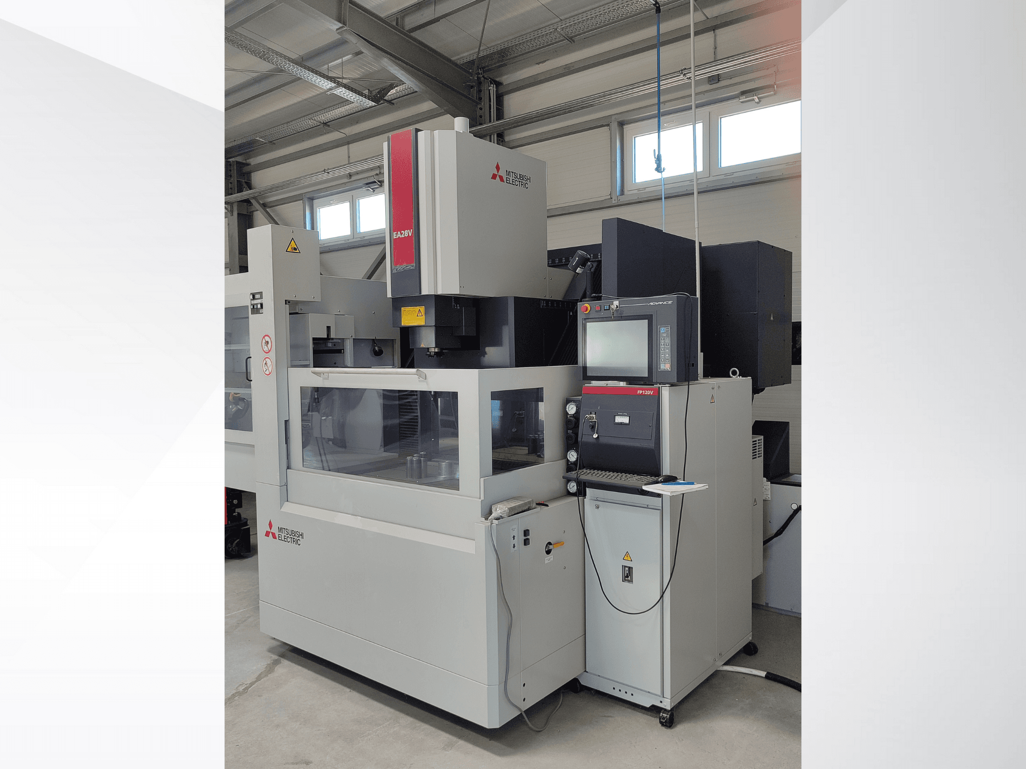 Mitsubishi Electric EA32V stiepļu griešanas EDM mašīna no sānu skata, ar vadības paneli un caur stiklu redzamu darba zonu.