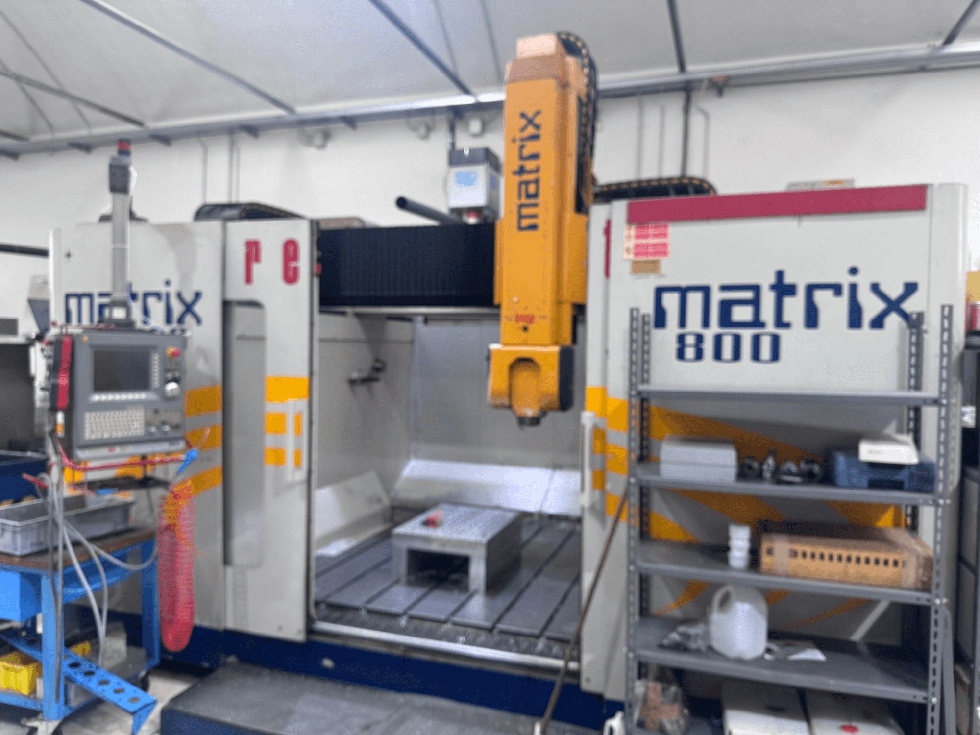 Matrix 800 CNC mašīna darbnīcas skatā ar vadības paneli, instrumentiem un darba galdu ar dažādiem priekšmetiem.