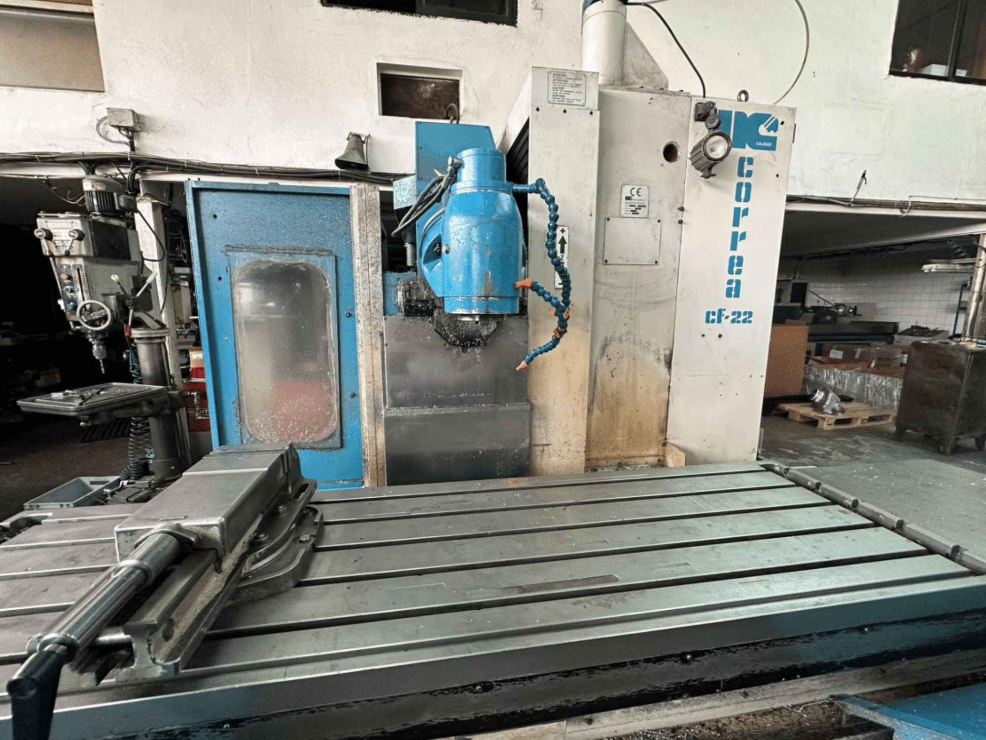 Correa CF-22 frēzmašīna, kas parādīta no priekšpuses, ar zilu un sudraba dizainu, bīdāmo galdu un griešanas galvu.
