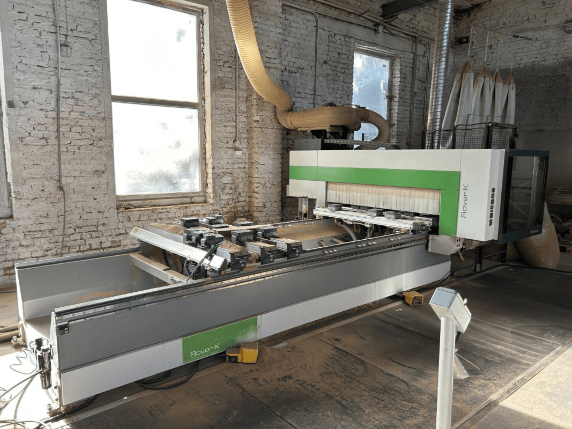 CNC apstrādes centrs BIESSE Rover K 1532 G darbnīcā, skats no priekšpuses, kur redzami tā griešanas instrumenti un darba virsma.