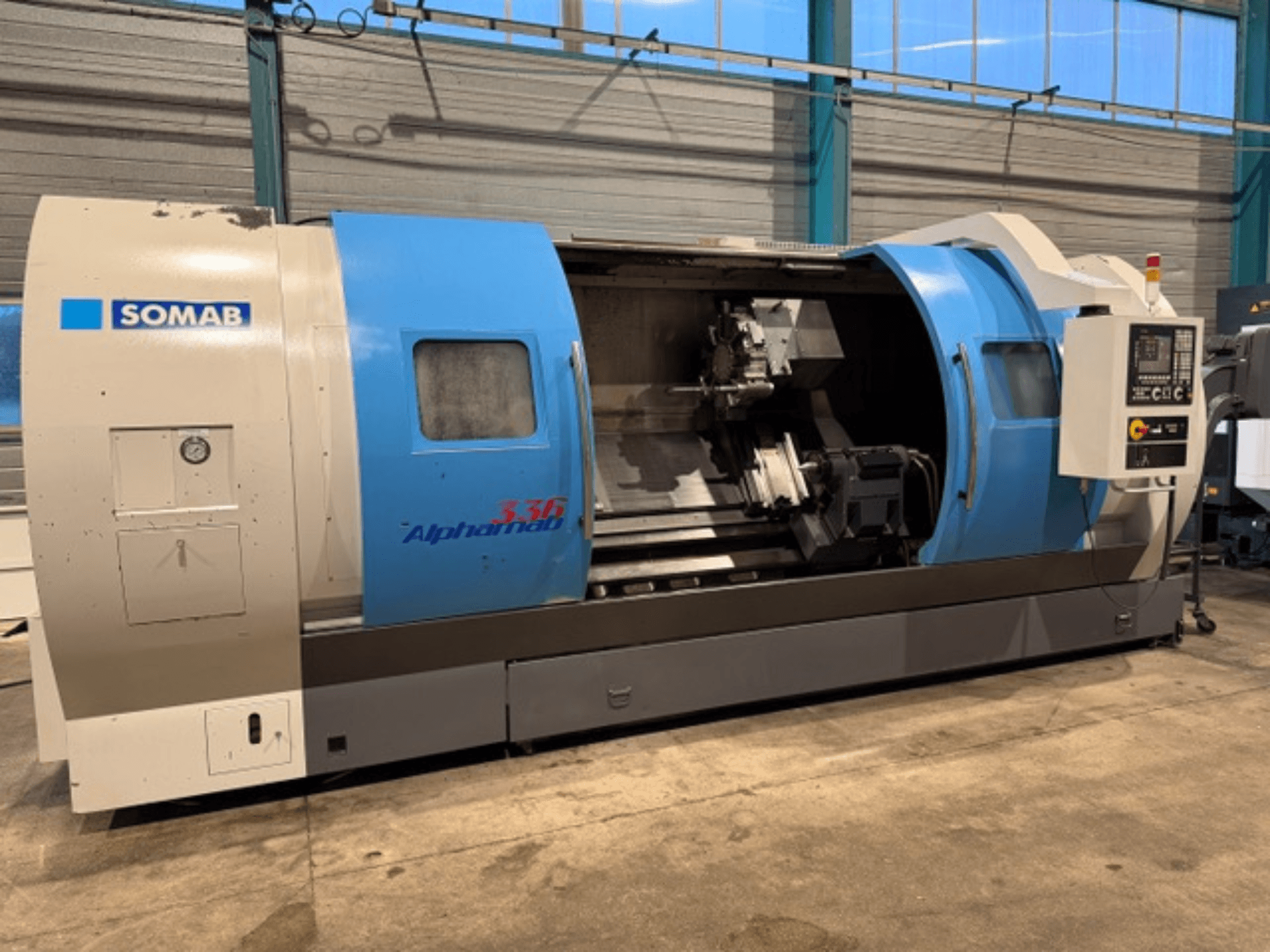 SOMAB Alpha 336 CNC virpa, skats no priekšpuses, ar zilu un pelēku korpusu un vadības paneli sānos.