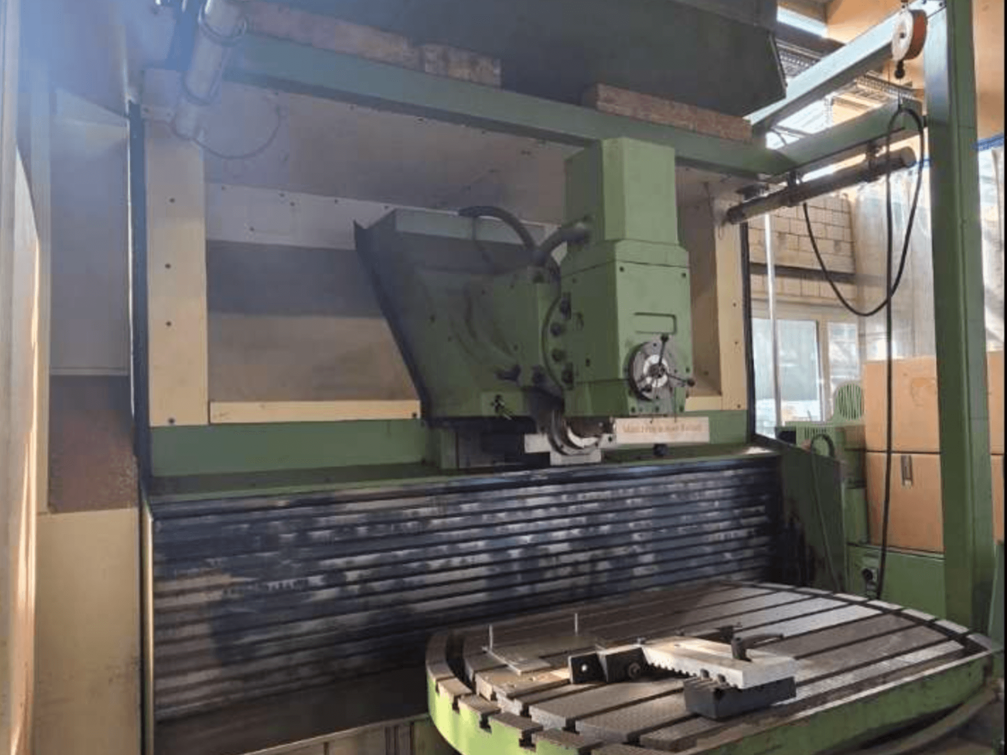 MAHO MH1000 C universālais apstrādes centrs priekšpusē, kurā redzama zaļā konstrukcija, vārpsta un rotācijas galds ar apstrādājamo detaļu.