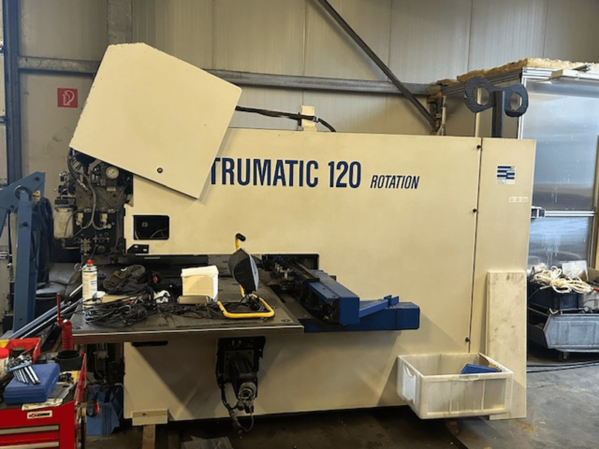 TRUMPF Trumatic 120R CNC caurumošanas iekārta darbnīcā, priekšējais skats, kurā redzams vadības panelis un instrumenti uz galda.