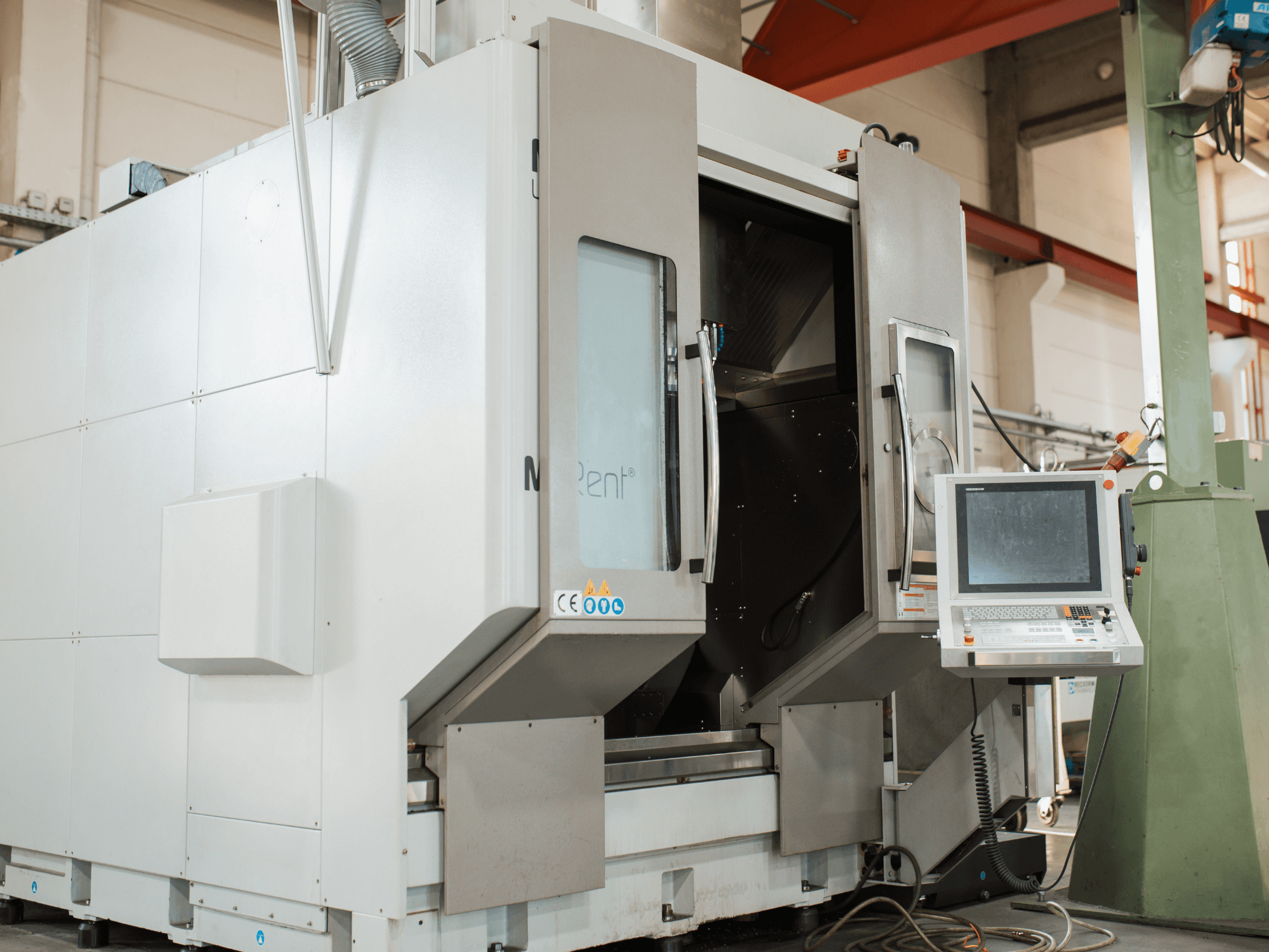 N Rent® CNC frēzmašīna, skats no priekšpuses, ar vadības paneli ar ekrānu, atvērtām durvīm un industriālu vidi.