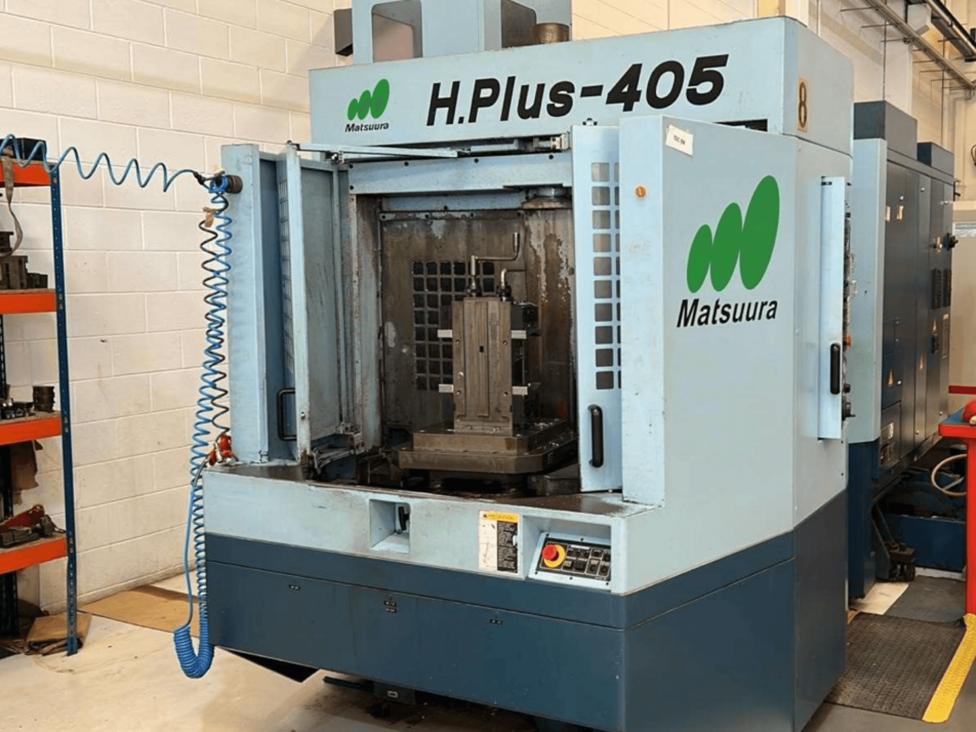 Matsuura H.Plus 405 horizontālā apstrādes centra skats no priekšpuses ar atvērtām durvīm, kurā redzama darba zona un vadības panelis.