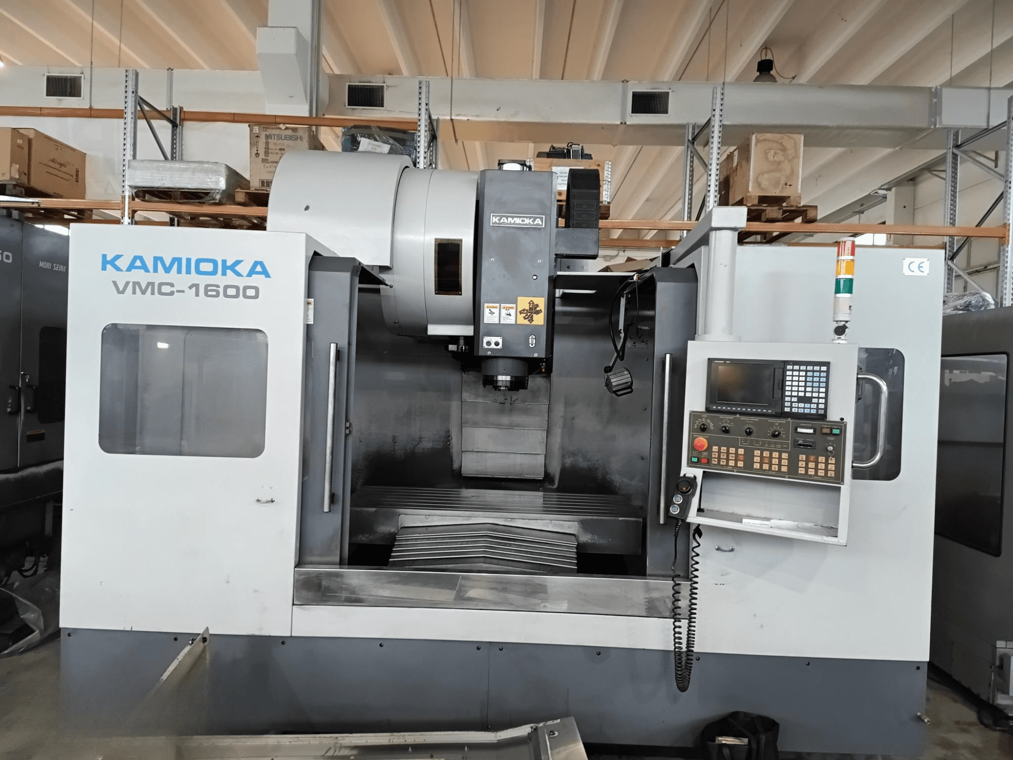 Kamioka VMC-1600 vertikālais apstrādes centrs rūpnīcā, skats no priekšpuses ar vadības paneli un redzamo apstrādes gultni.