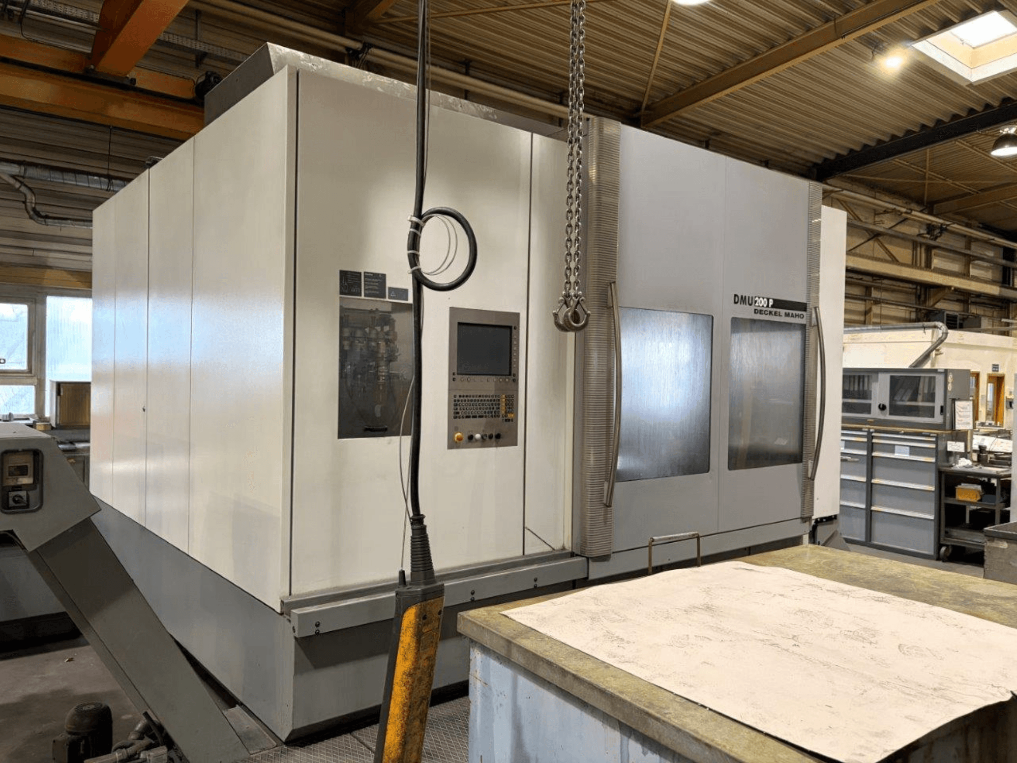 DMG MORI DMU 200 universālais apstrādes centrs DMG MORI DMU 200 darbnīcā, priekšējais skats, kurā redzams tā vadības panelis un ārējās iezīmes.