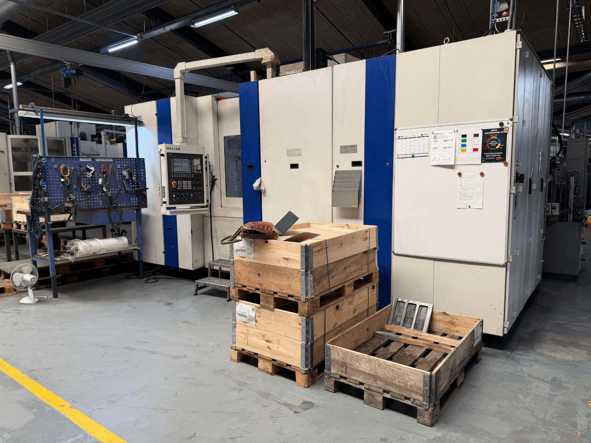 HORIZONTĀLĀ APSTRĀDE HELLER MCH 250 darbnīcā, skats no sāniem, redzami koka paliktņi un instrumentu statīvs.