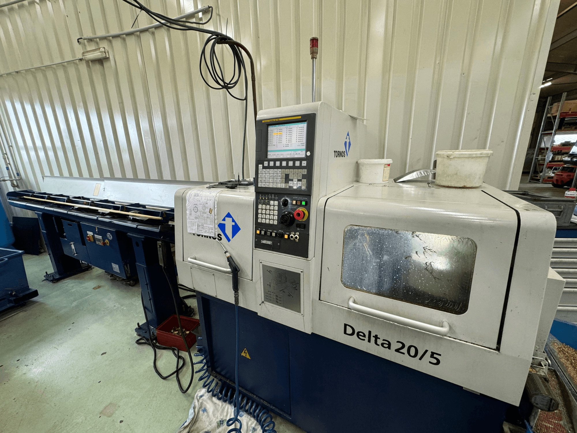 Torino Delta 20/5 CNC darbgalds, skats no priekšpuses, ar vadības paneli un darba vietu. Iezīmē gravētu stiklu un redzamus vadus.