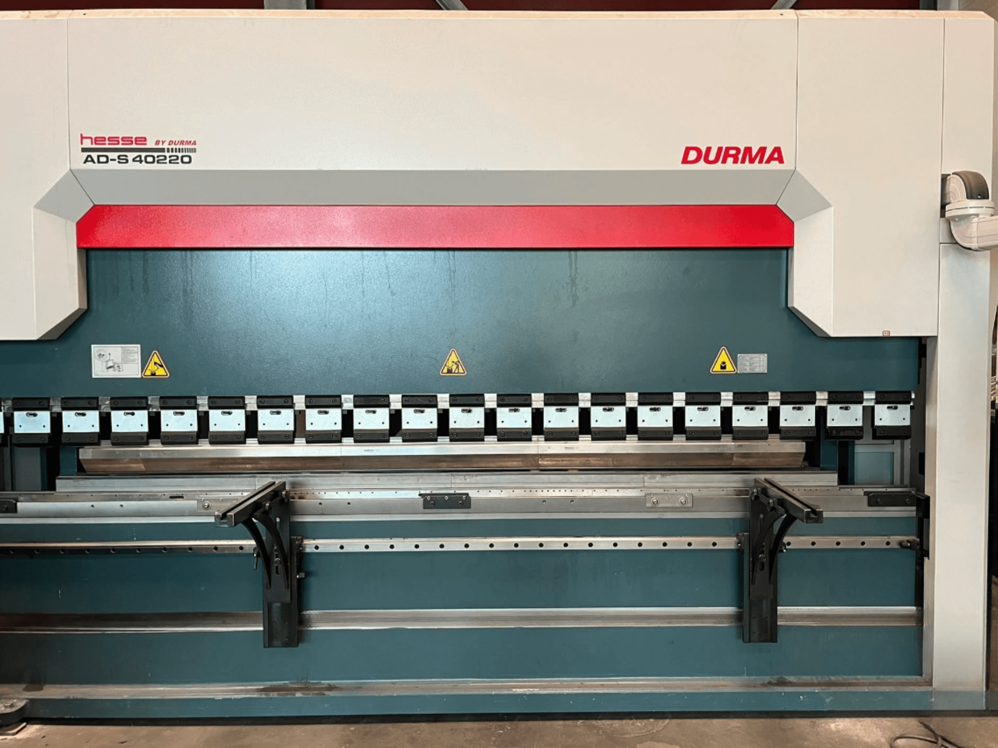 Durma AD-S 40220 lieces preses skats no priekšpuses, kurā redzami vairāki lieces rīki un drošības uzlīmes.
