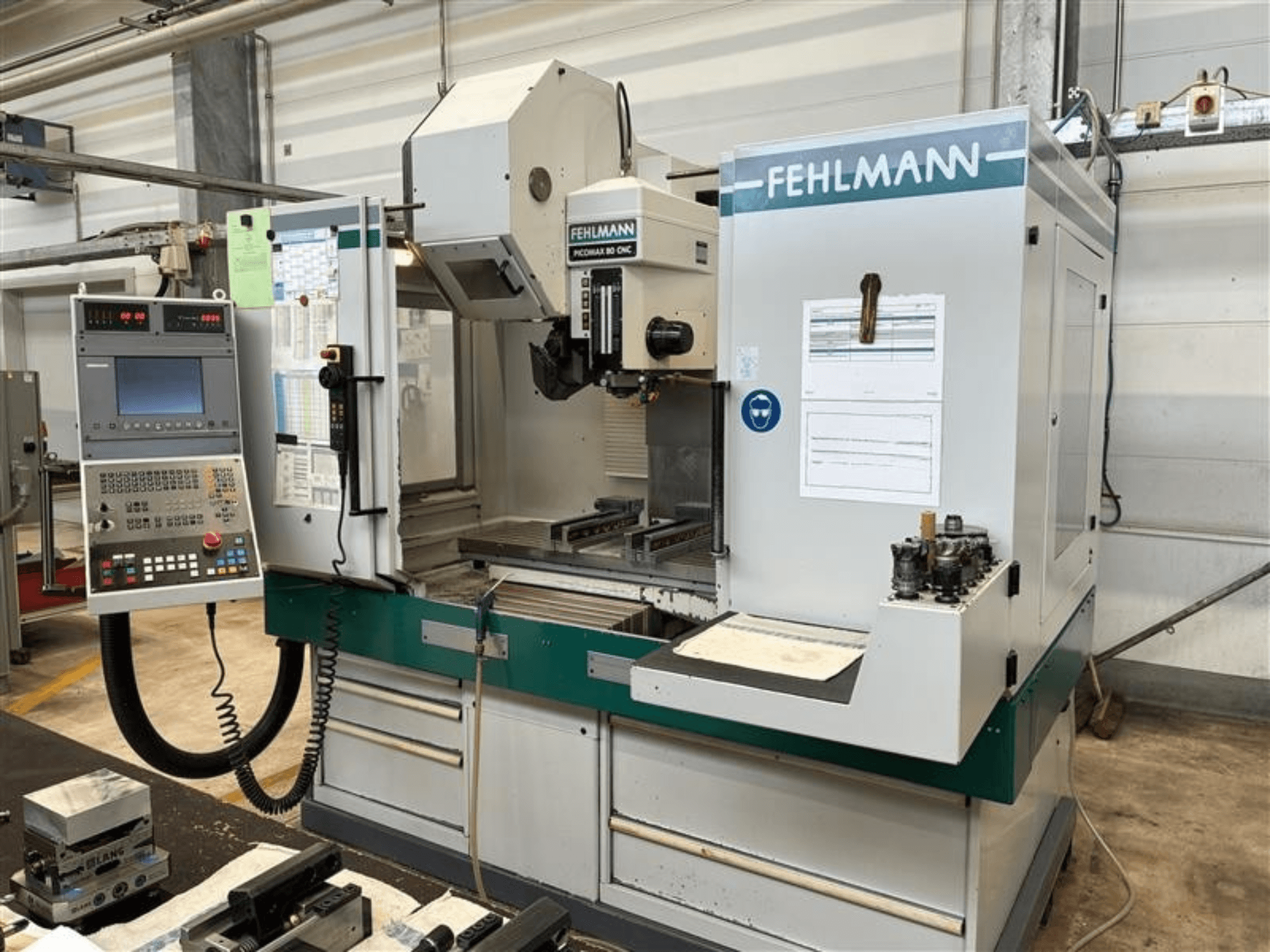 FEHLMANN PICOMAX 80 CNC-W 2/3 vertikālais apstrādes centrs, redzams no priekšpuses, ar vadības paneli un apstrādes darba zonu.