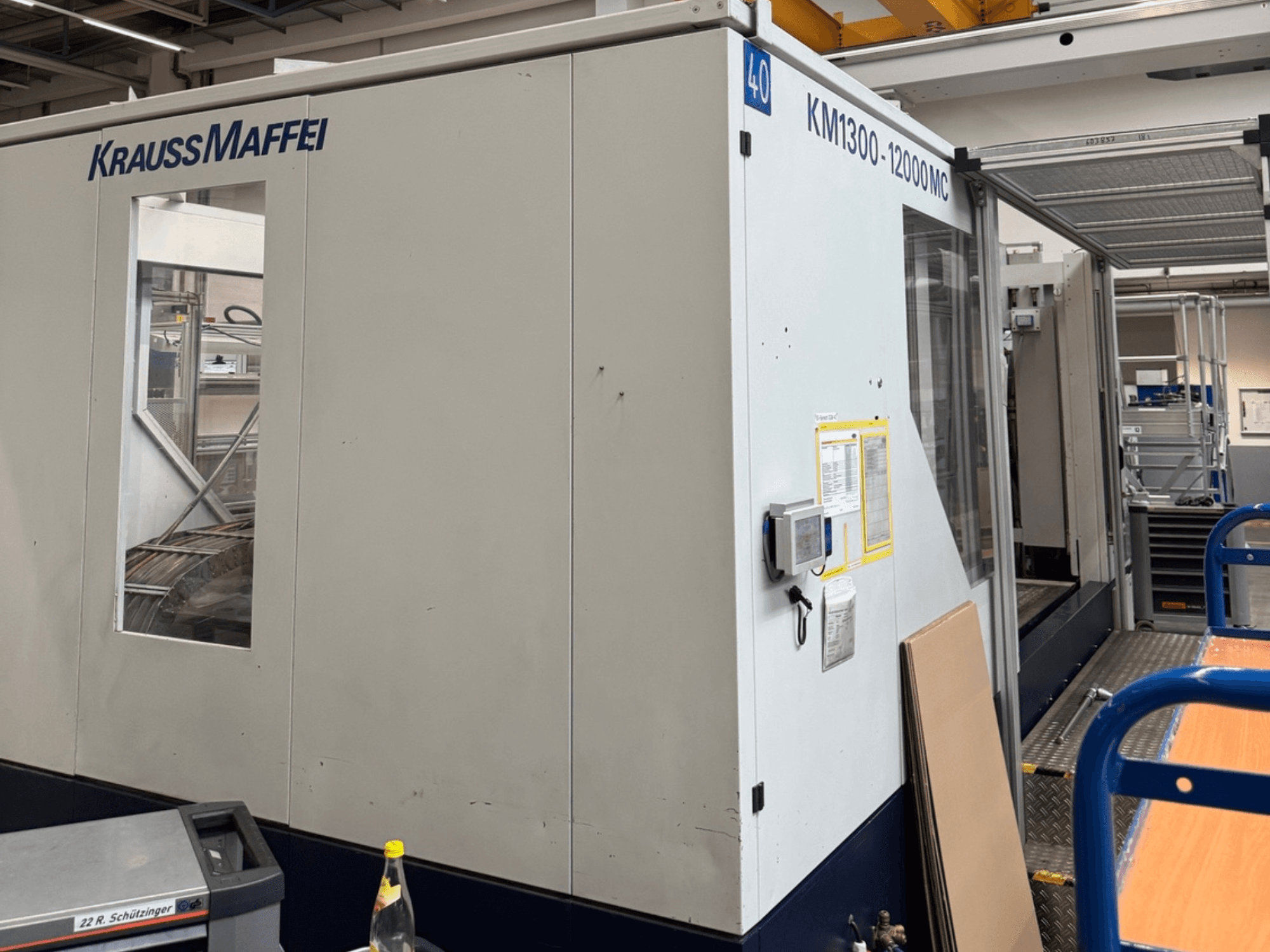 Krauss Maffei hidrauliskā iesmidzināšanas iekārta KM1300-12000 MC, skats no sāniem, redzams vadības panelis un darba telpa.