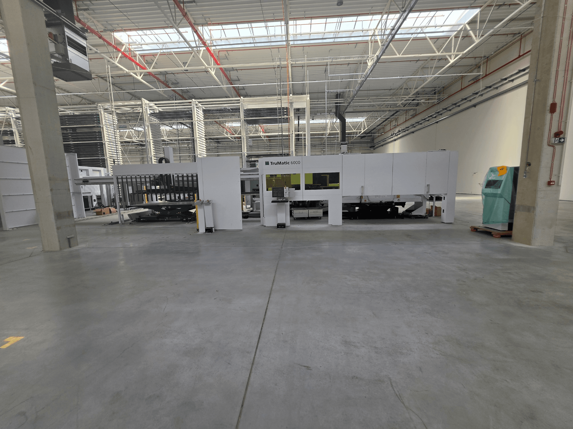 TRUMPF TruMatic 6000-1600 optiskās šķiedras perforācijas un lāzera kombinētā mašīna plašā noliktavā, skats no priekšpuses.
