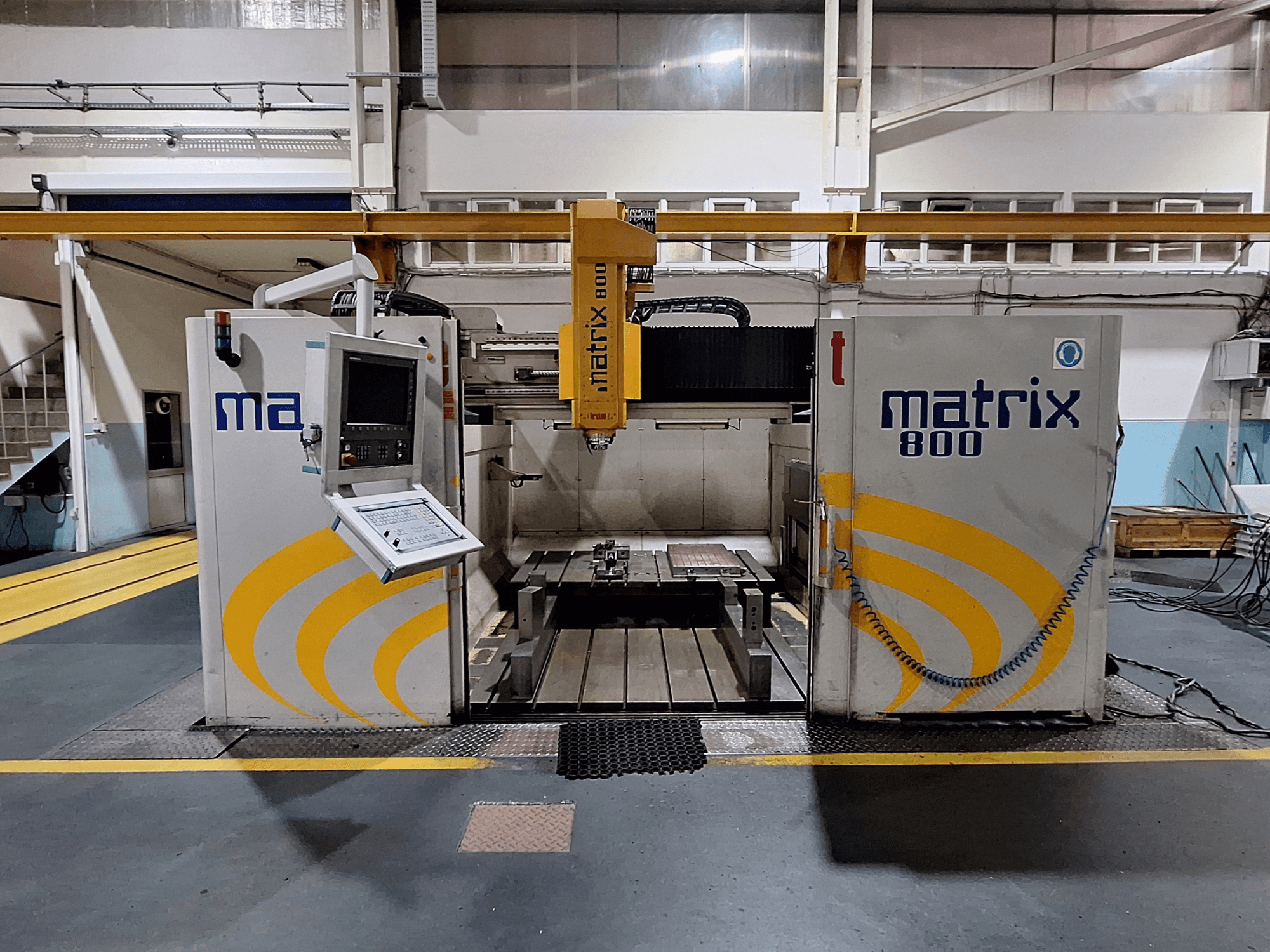 Portālfrēzmašīna Breton Matrix WM 800 K25 darbnīcā, vadības panelis un darbagalds no priekšpuses.