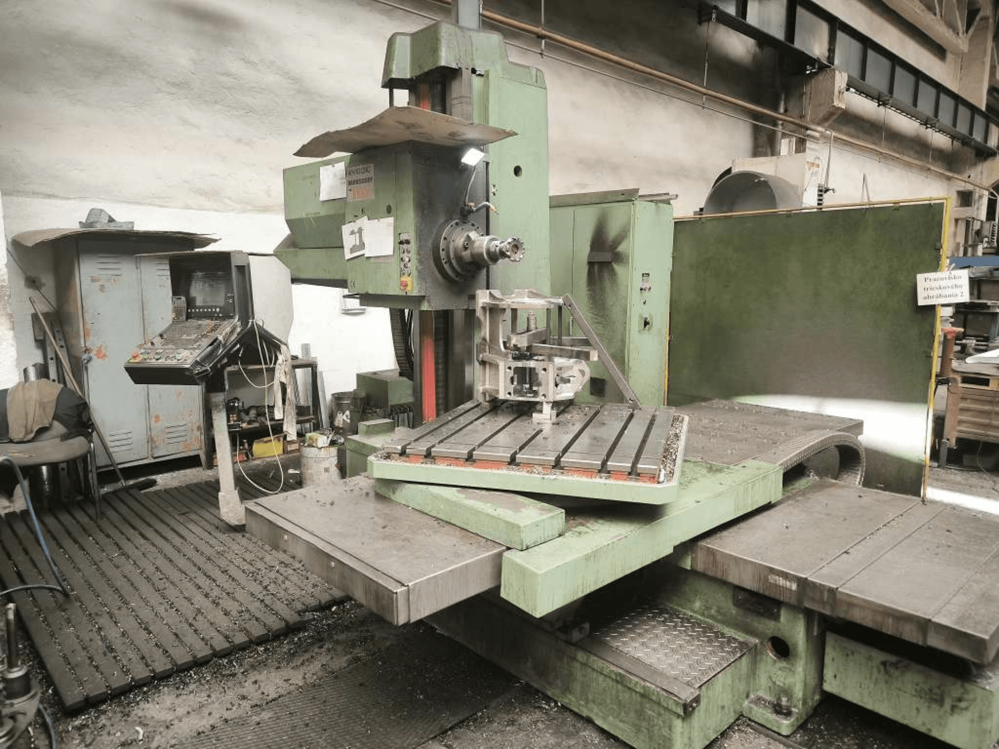 TOS WH 10 CNC urbšanas stends, skats no priekšpuses, kurā redzams apstrādāts detaļas gabals uz galda un vadības panelis.