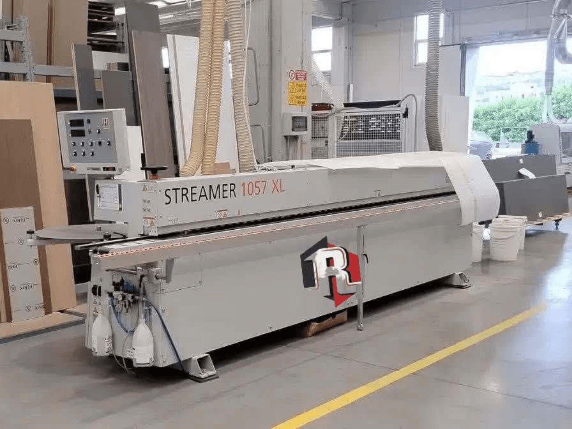 HOLZHER STREAMER 1057 XL malu līmēšanas mašīna darbnīcā, skats no sāniem ar redzamu vadības paneli un gaisa šļūtenēm.