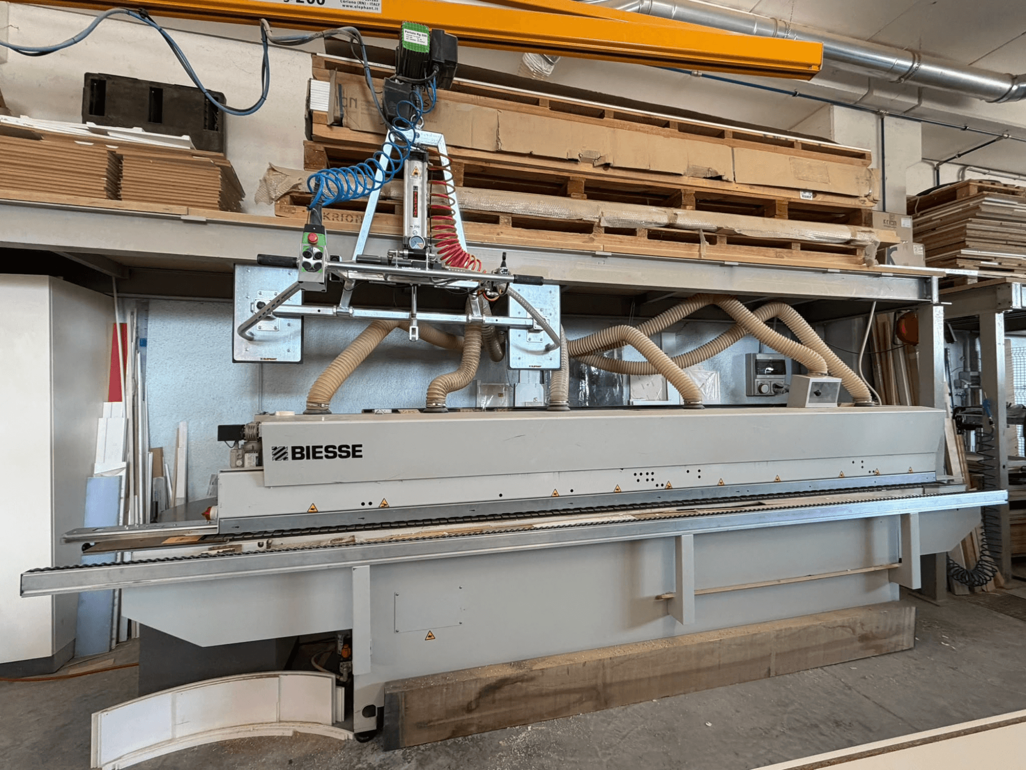 BIESSE AKRON 1330 malu līmēšanas mašīna darbnīcā, redzama no priekšpuses ar vadības paneli un putekļu nosūces sistēmu.