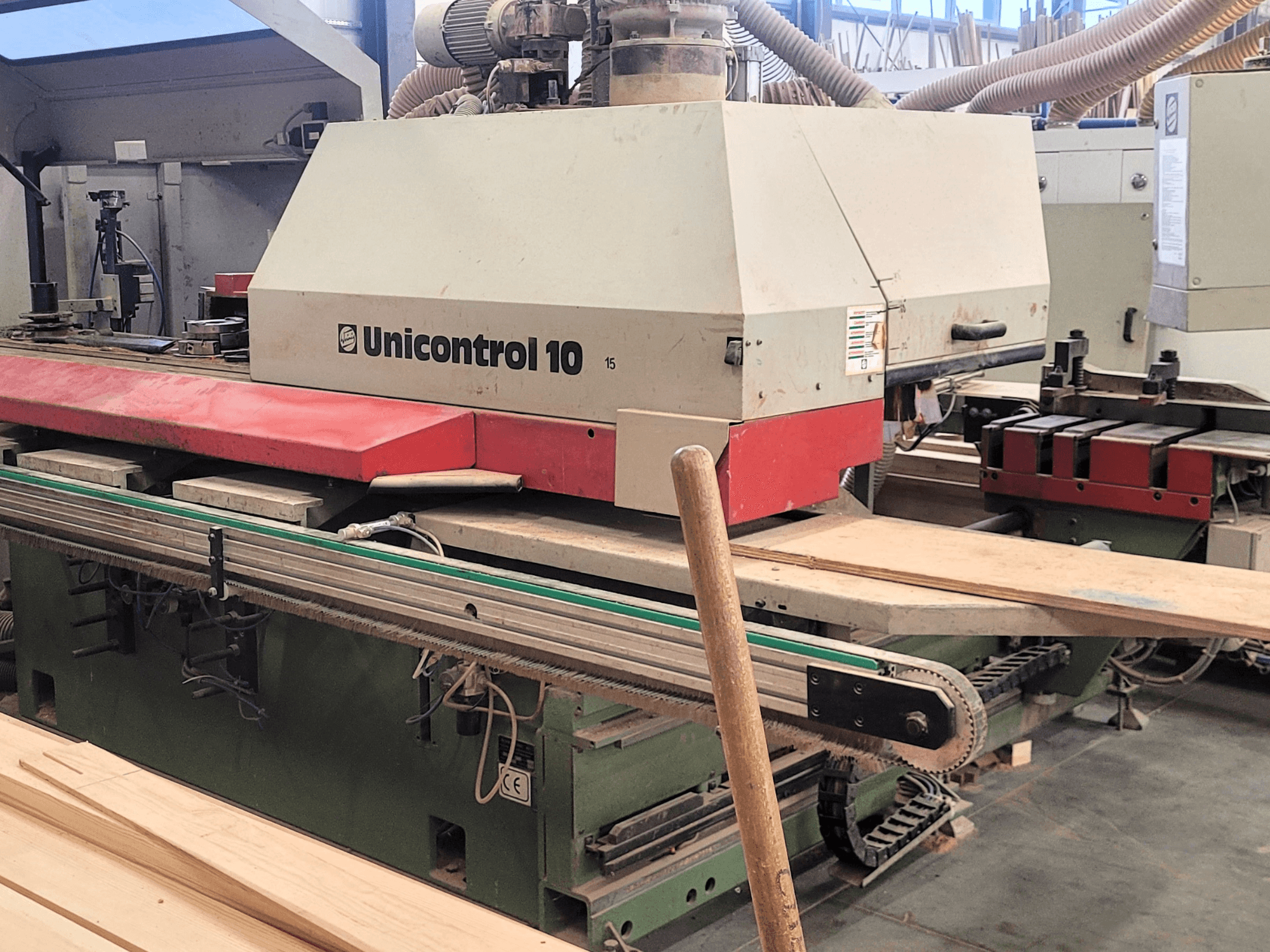 WEINIG/DIMTER CNC apstrādes centrs Unicontrol 10, priekšējais skats ar koka dēļiem un iekārtām darbnīcā.