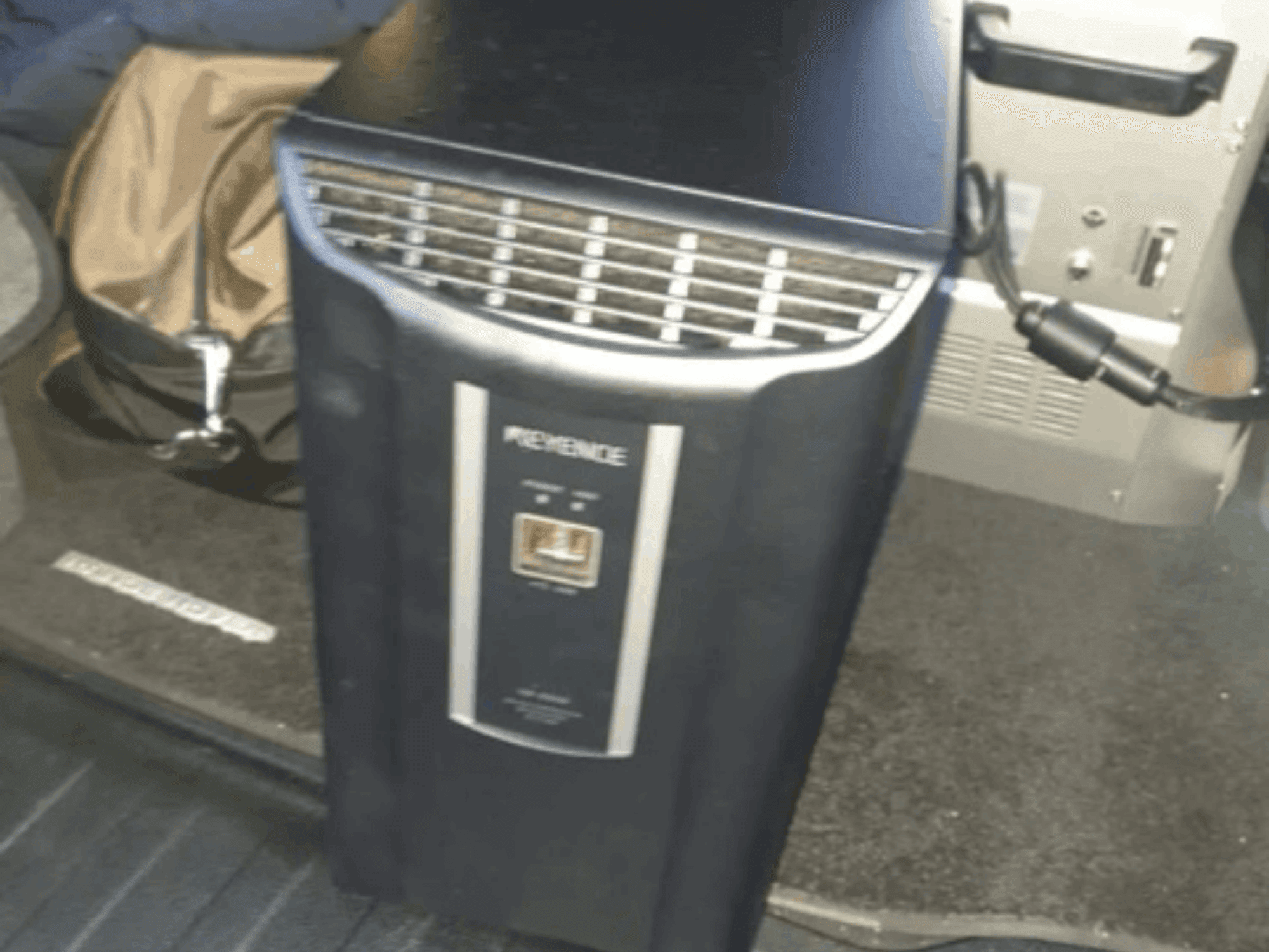 KEYENCE IM-8030 automatizācijas sistēma priekšpusē, kurā redzams vadības panelis un ventilācijas atveres uz transportlīdzekļa salona fona.