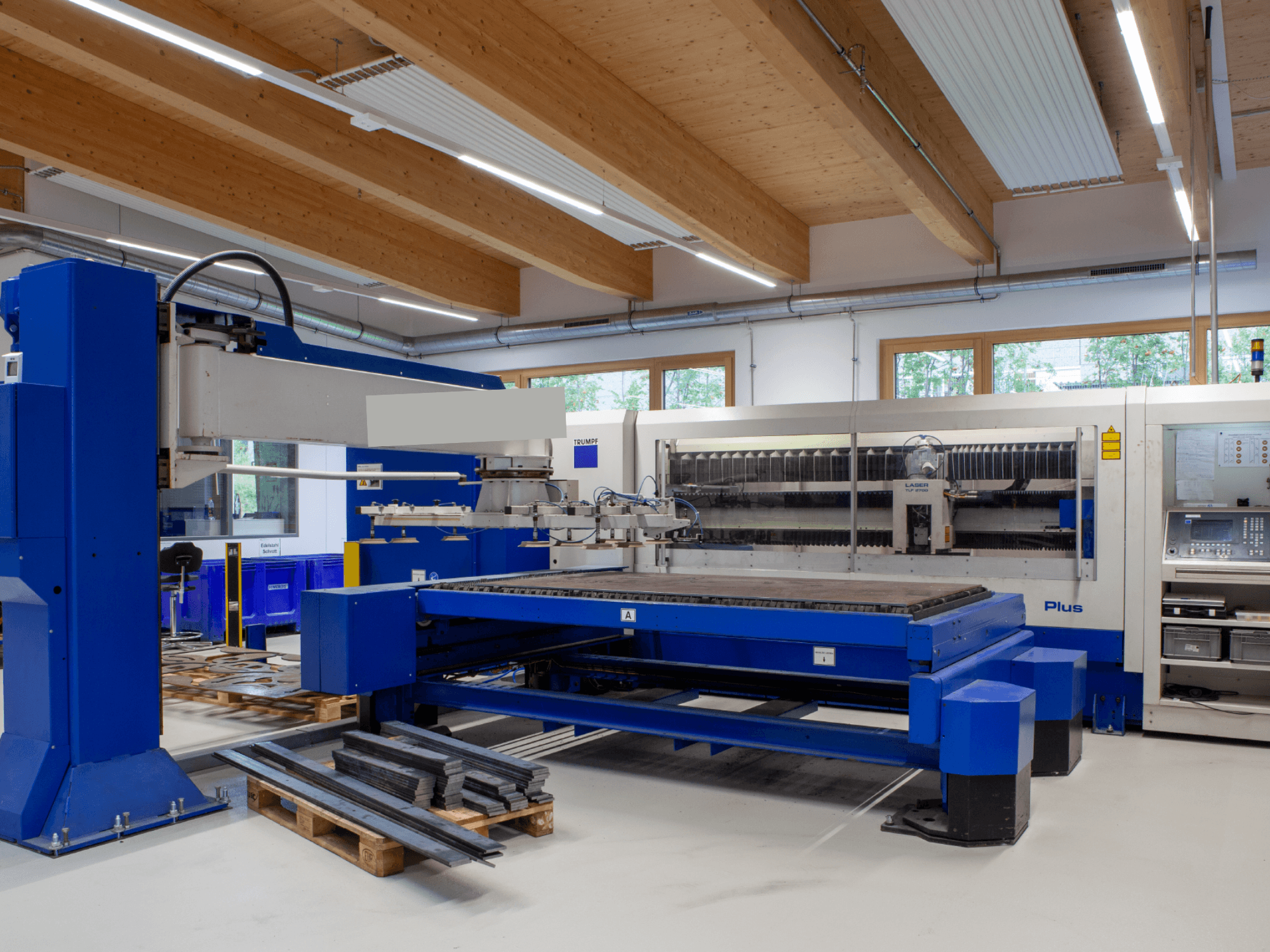 TRUMPF TRUMATIC L 2530 Plus CO₂ lāzergriešanas iekārta darbnīcā, kas izceļas ar plašu griešanas virsmu un rūpniecisko dizainu.