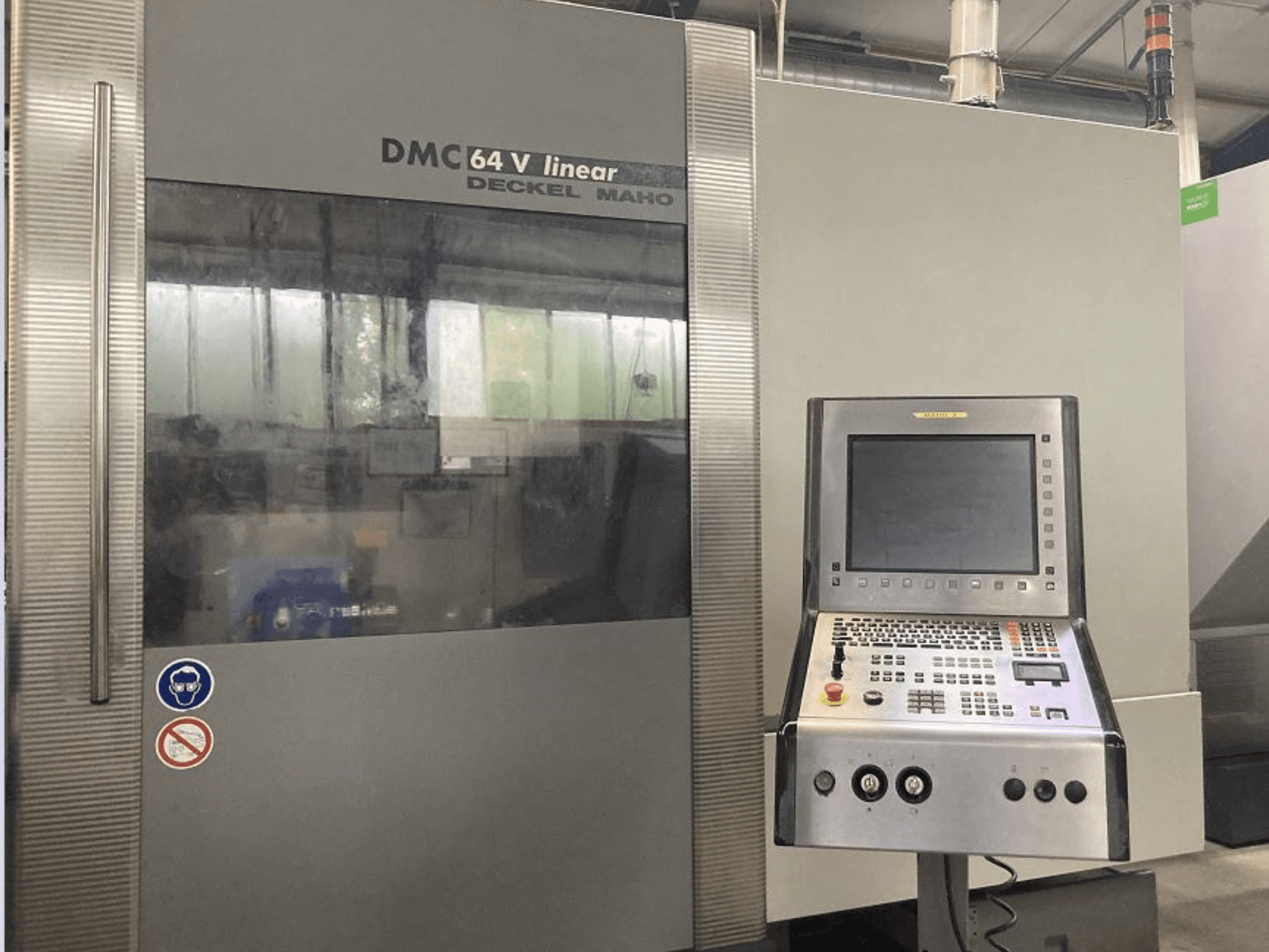 DMG DECKEL MAHO DMC 64V lineārais vertikālais apstrādes centrs, priekšējais skats ar vadības paneli un displeju.