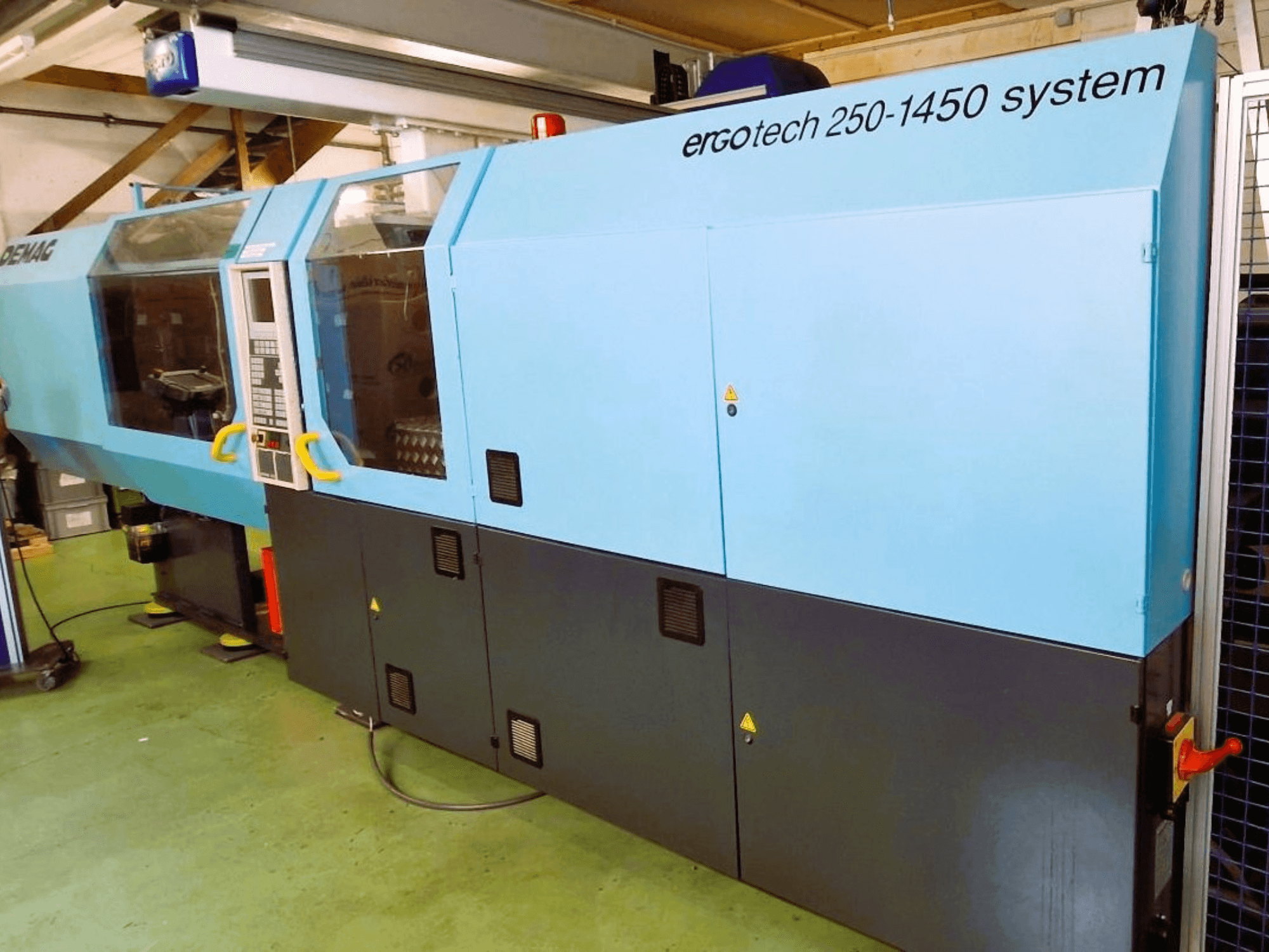 Ergotech 250-1450 sistēmas iesmidzināšanas iekārta, skats no priekšpuses, zilā un melnā krāsā, ar redzamu vadības paneli un drošības elementiem.